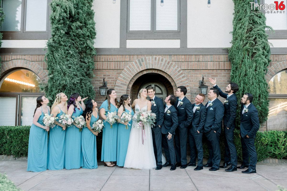 Bride and Groom pose with the wedding party as the wedding party blows kisses at them