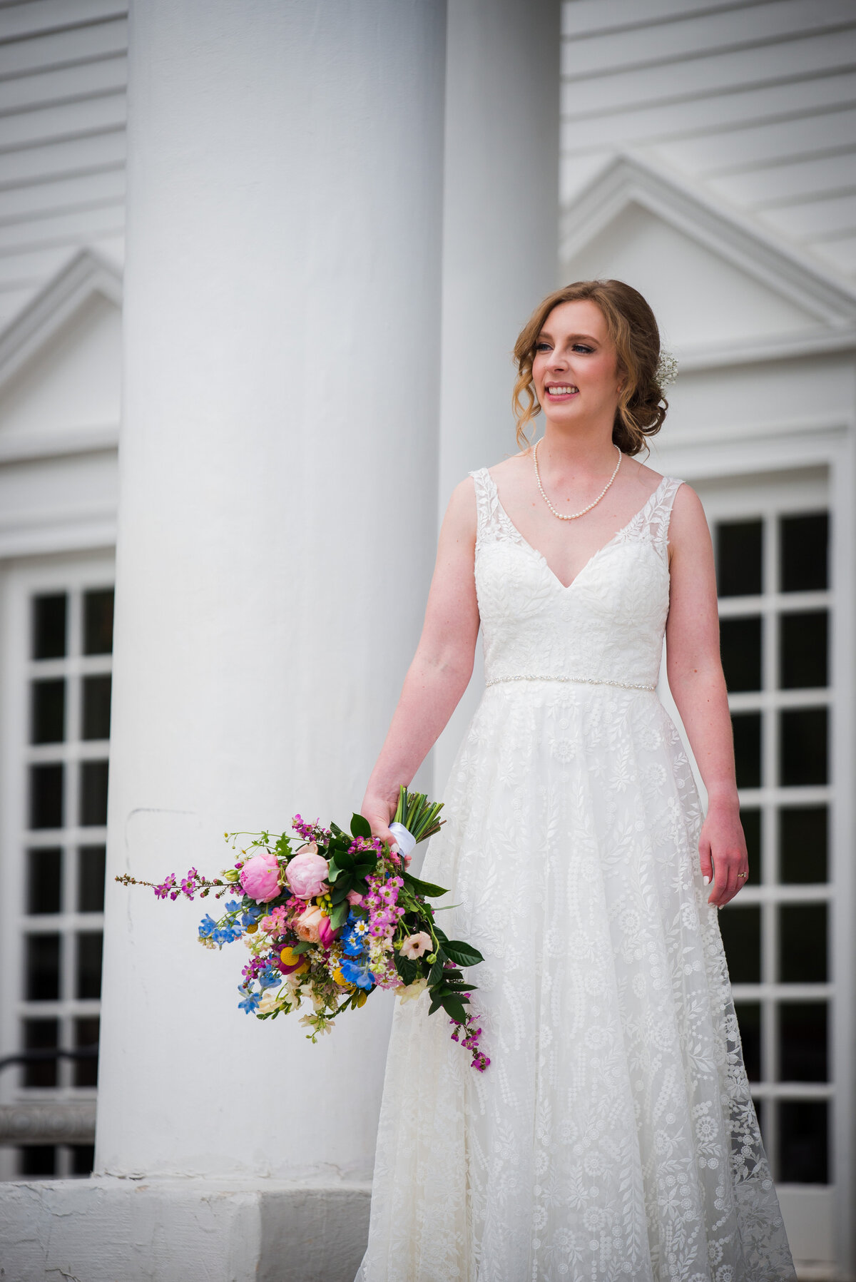 A bride glances off into the distance on the steps of the Manor House in Littleton, Colorado.
