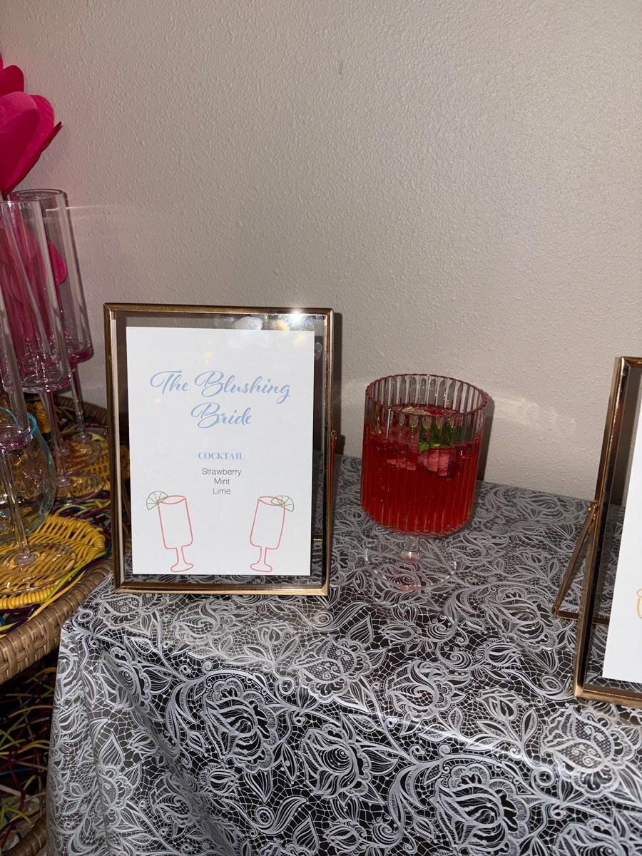 modern gold frame bachelorette themed cocktail sign with custom illustration. "the blushing bride" cocktail name with ingredients list