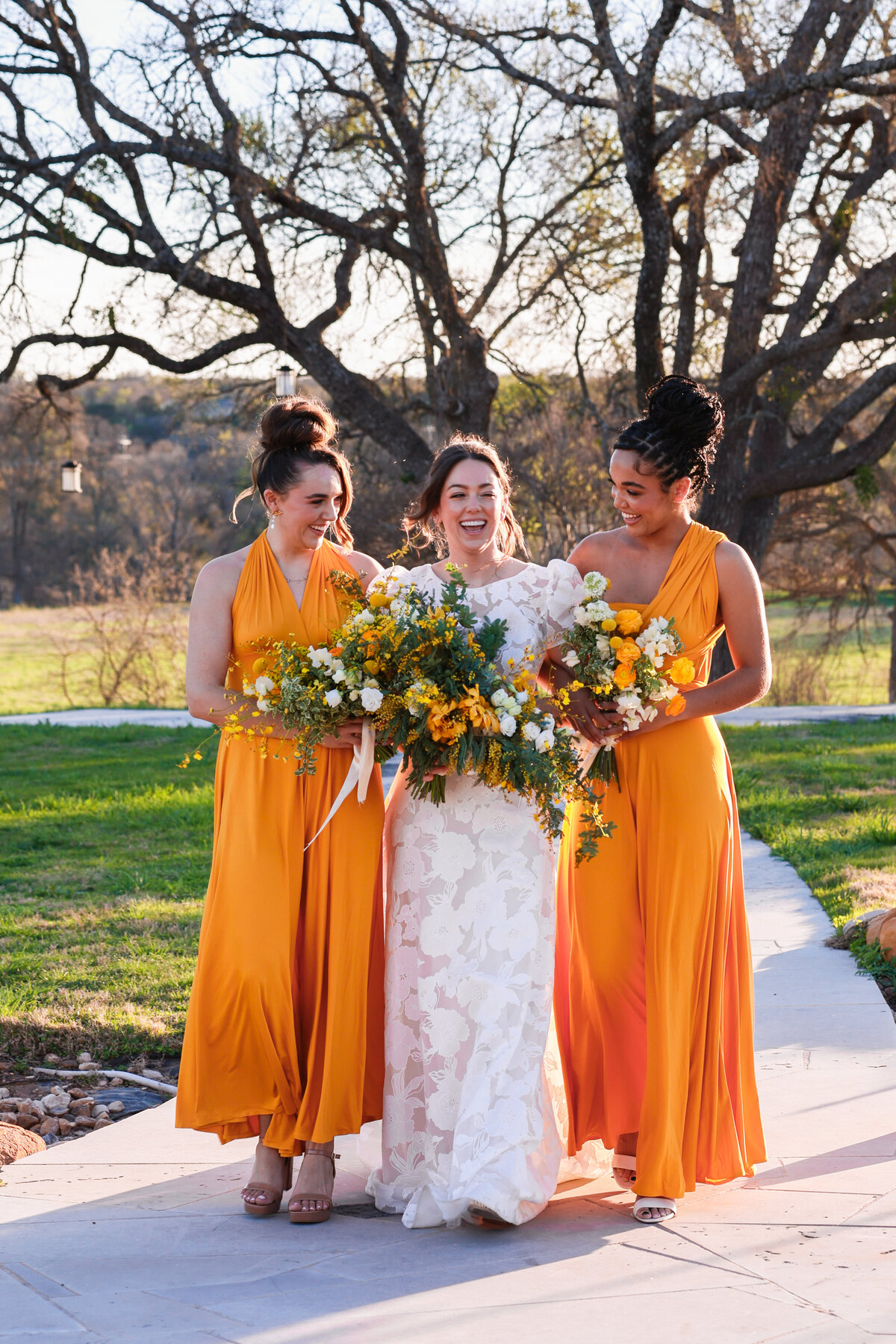 bride and bridesmaids wearing yellow dresses and holding yellow floral bouquets at Hewitt Oaks in Austin Texas by Austin Texas wedding photographer Amanda Richardson Photography