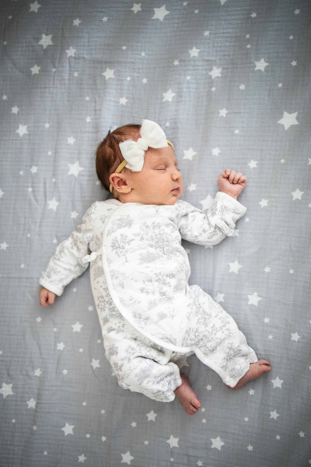 Baby girl laying on gray crib sheet with stars