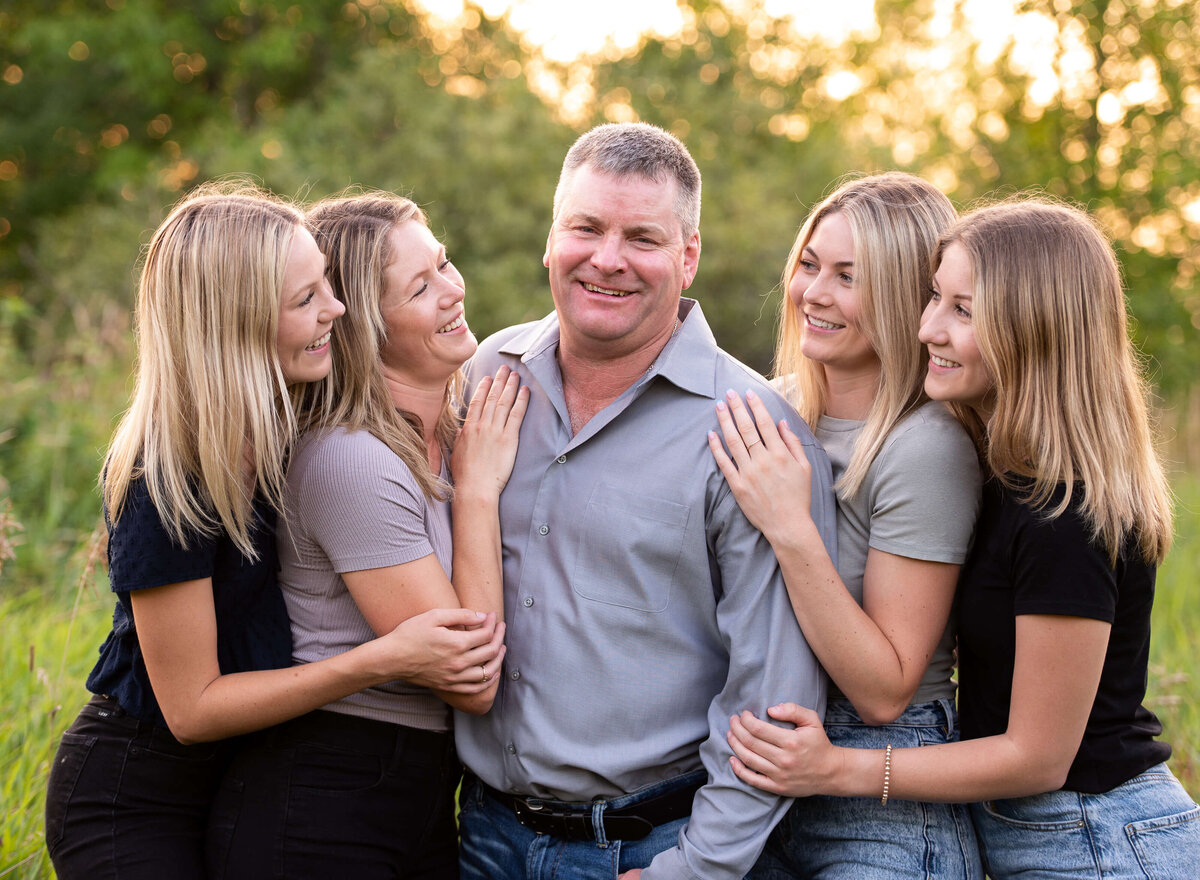a father laughs and smiles with his adult daughters.  Captured by Ottawa Family Photographer JEMMAN Photography