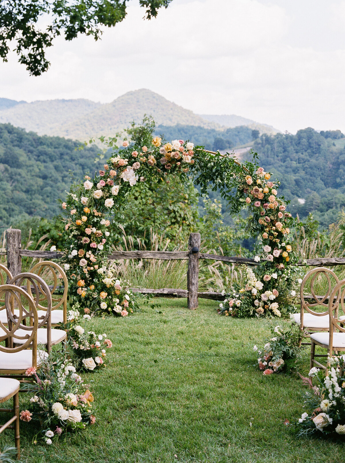 Romantic floral wedding arch surrounded by chairs and mountain views at Castle Ladyhawke venue in North Carolina.
