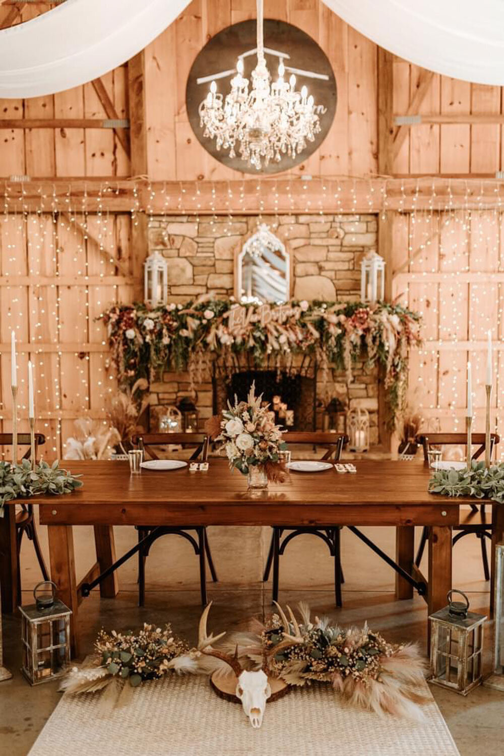 Rustic barn dining setup with a decorated fireplace and wooden table