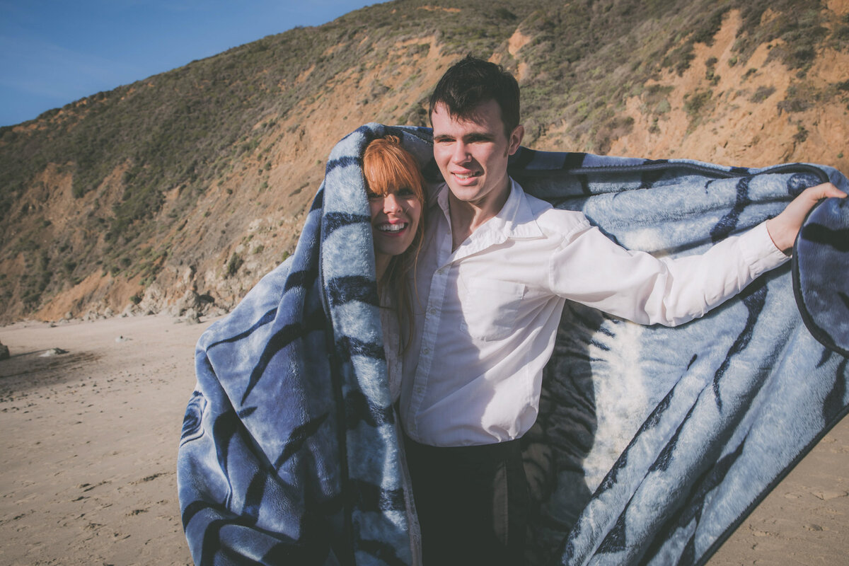 Couple smiles at Seeking Venture Photo while curling up in blanket.