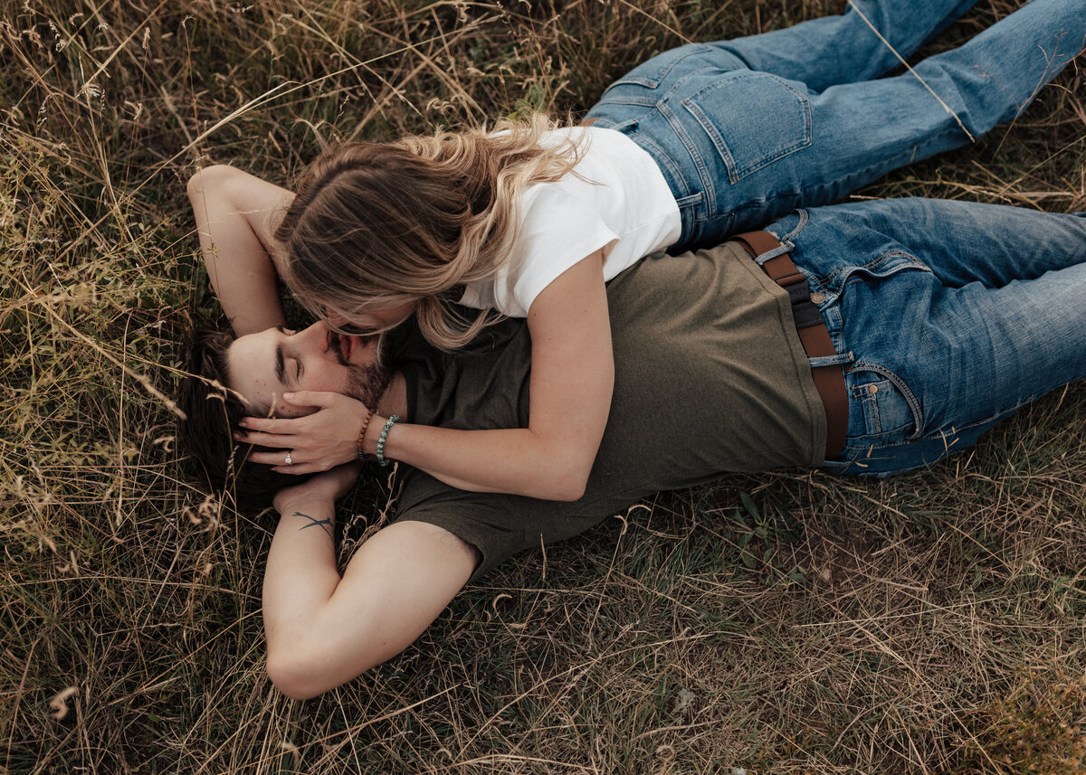Engaged couple cuddling in a field