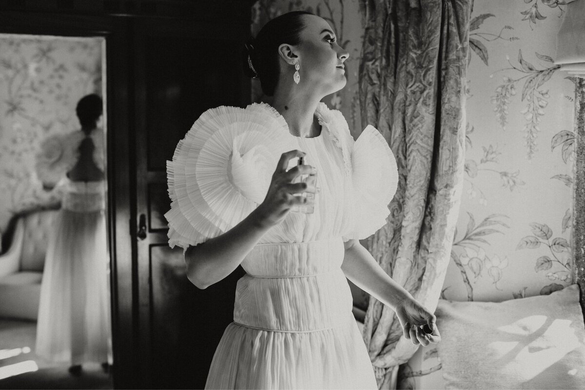 Black and white photo of bride applyong perfume ahead of ceremony