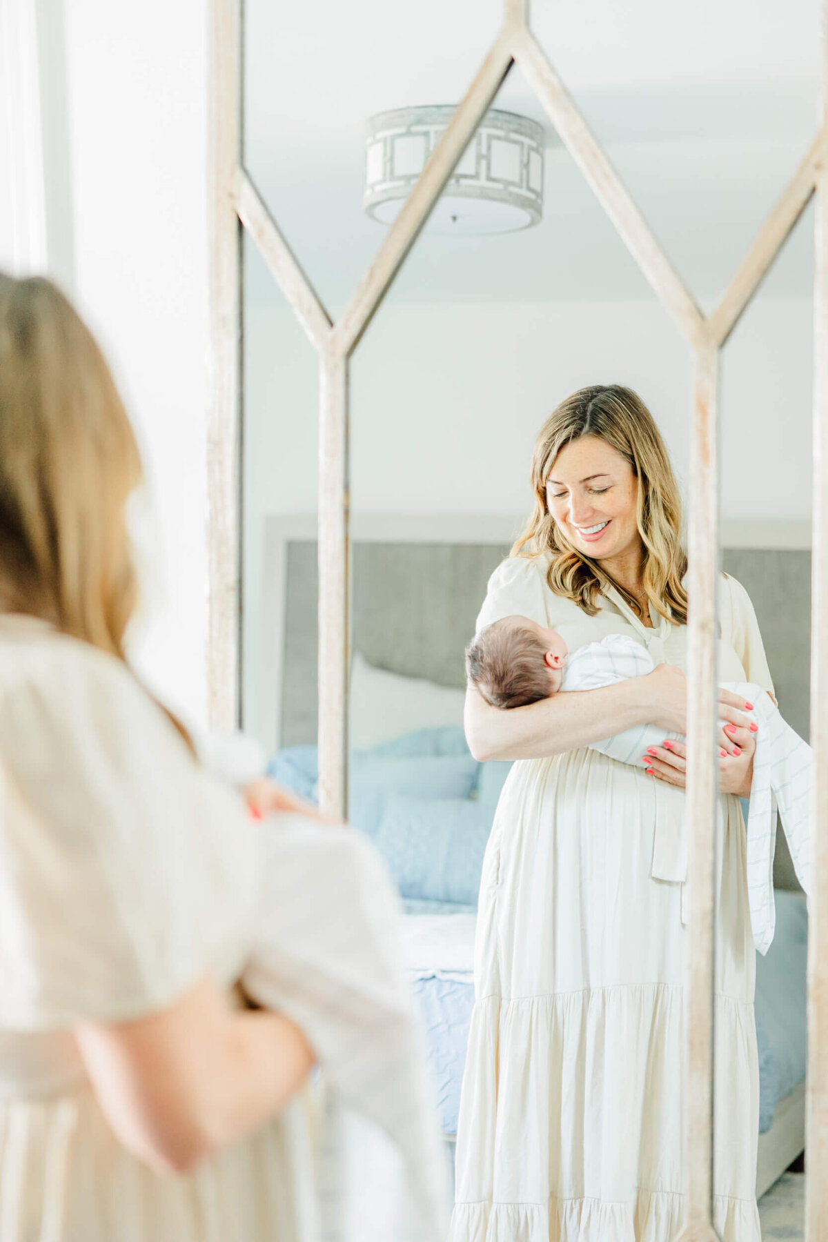 Reflection in a mirror shows a Boston mom holding her newborn baby