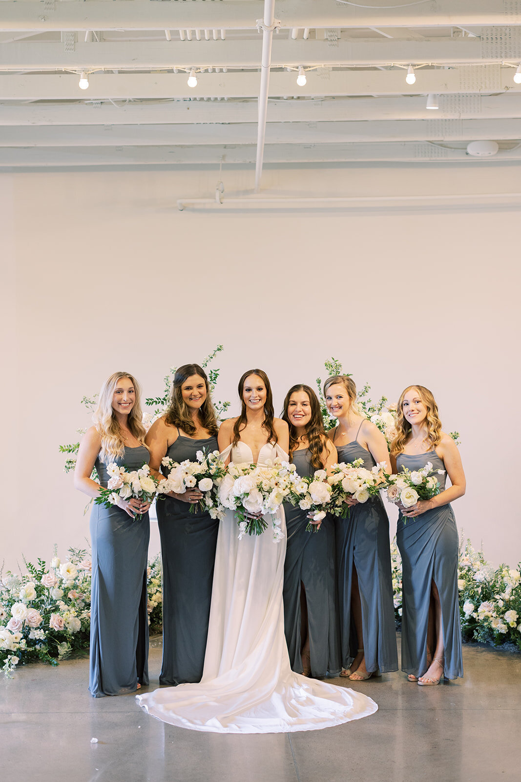 Bridal party florals of white garden roses, peonies, ranunculus, sweet peas, scabiosa, butterfly ranunculus and dark greenery in floral hues of white, cream, and blush. Designed by Rosemary and Finch in Nashville, TN.
