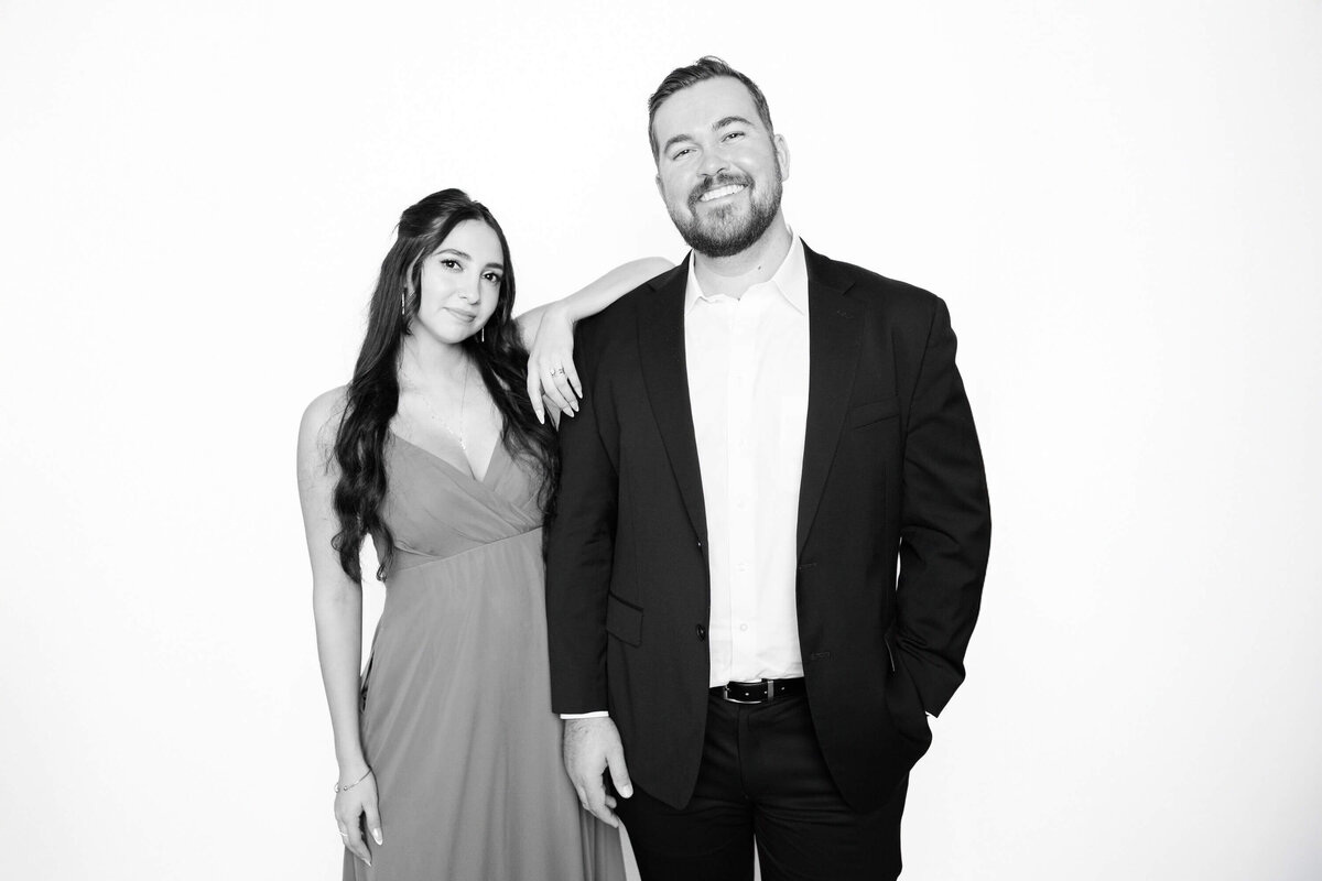 Man in a suit and woman in a gown posing confidently in a black and white portrait by Monochrome Portraits, a modern Phoenix photo booth experience.