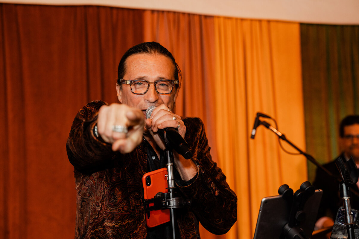A photograph of a band member singing at a wedding.