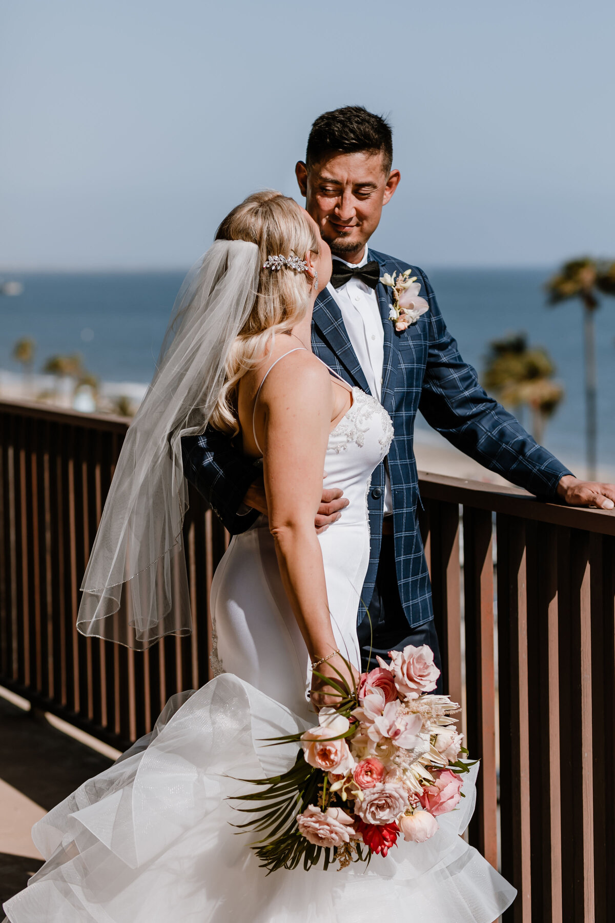 bride stands with arm around bride on balcony