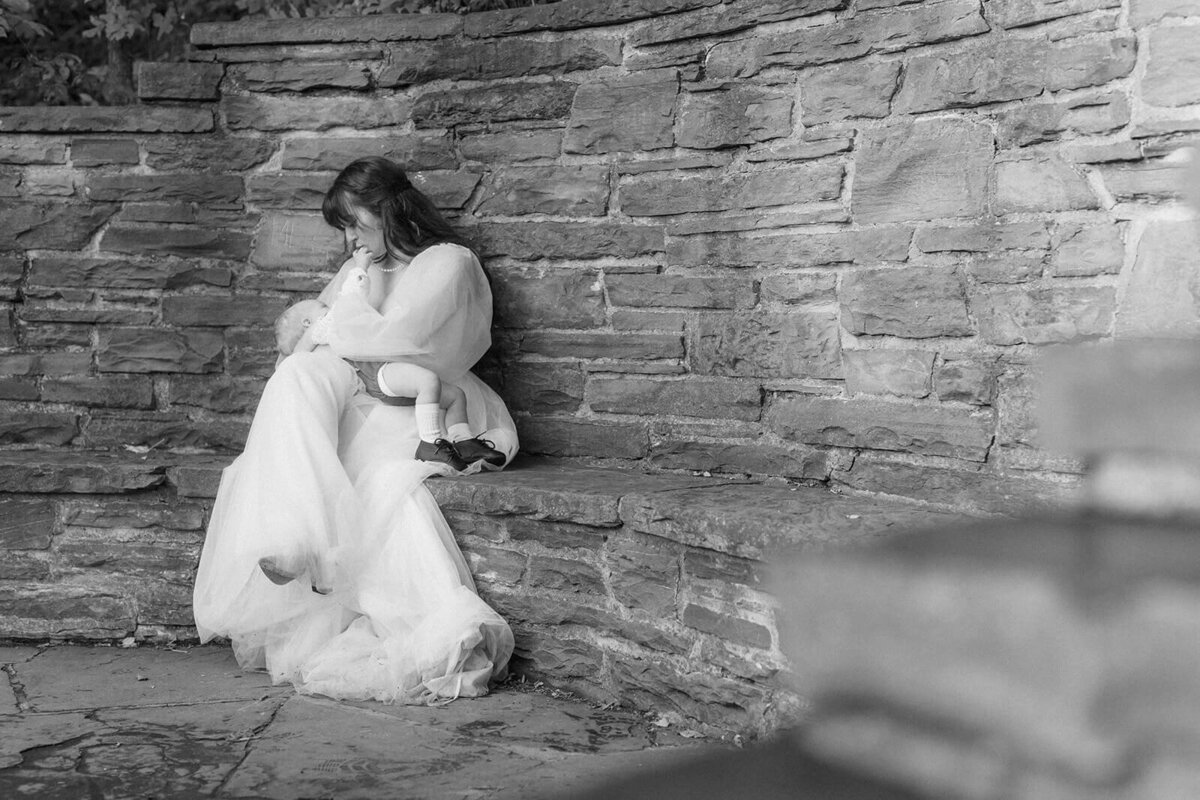 Bride sitting down breastfeeding baby