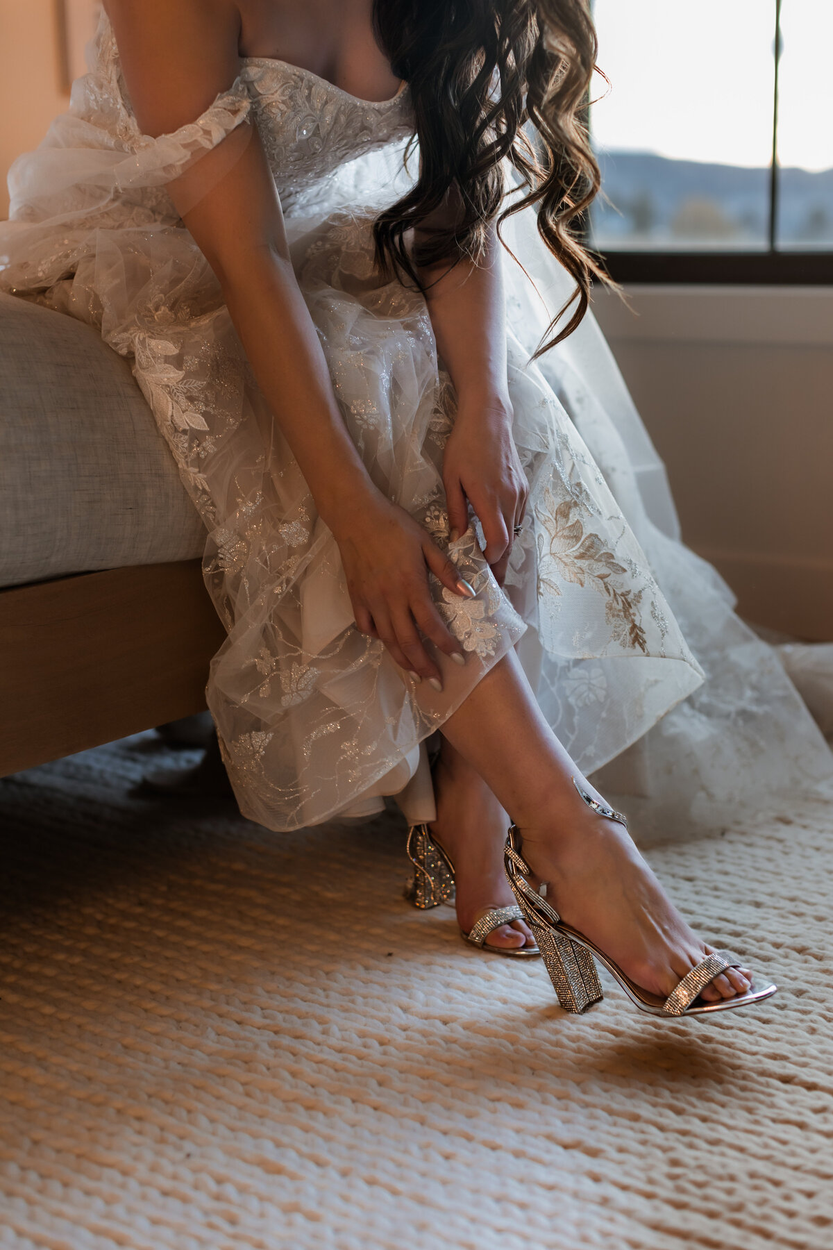 Bride putting on silver strappy heels.