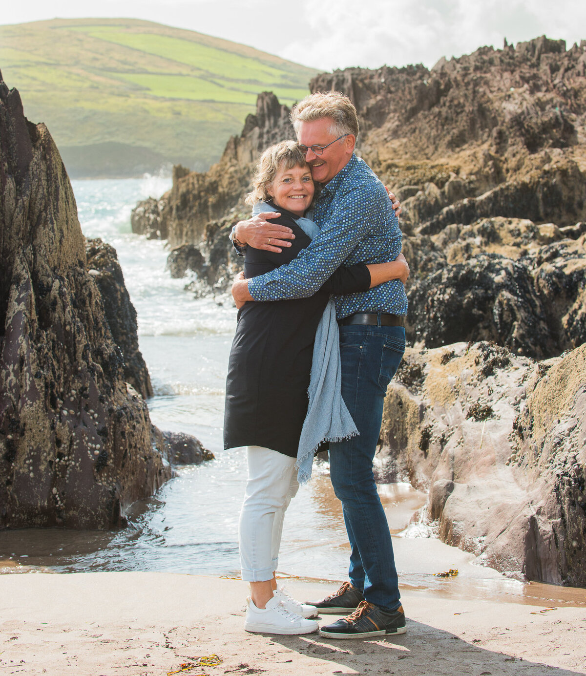 retired couple hugging and laughing on a beach