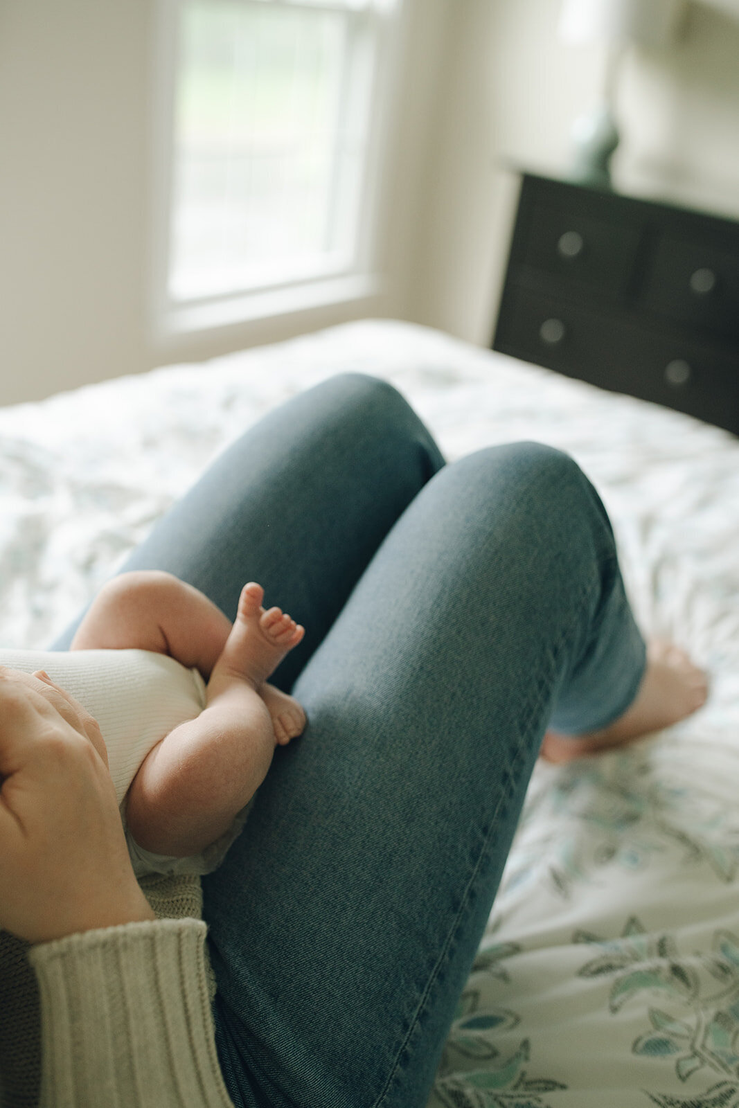 Close-up detail of mother’s feet next to her newborn baby’s tiny feet during a relaxed in-home session