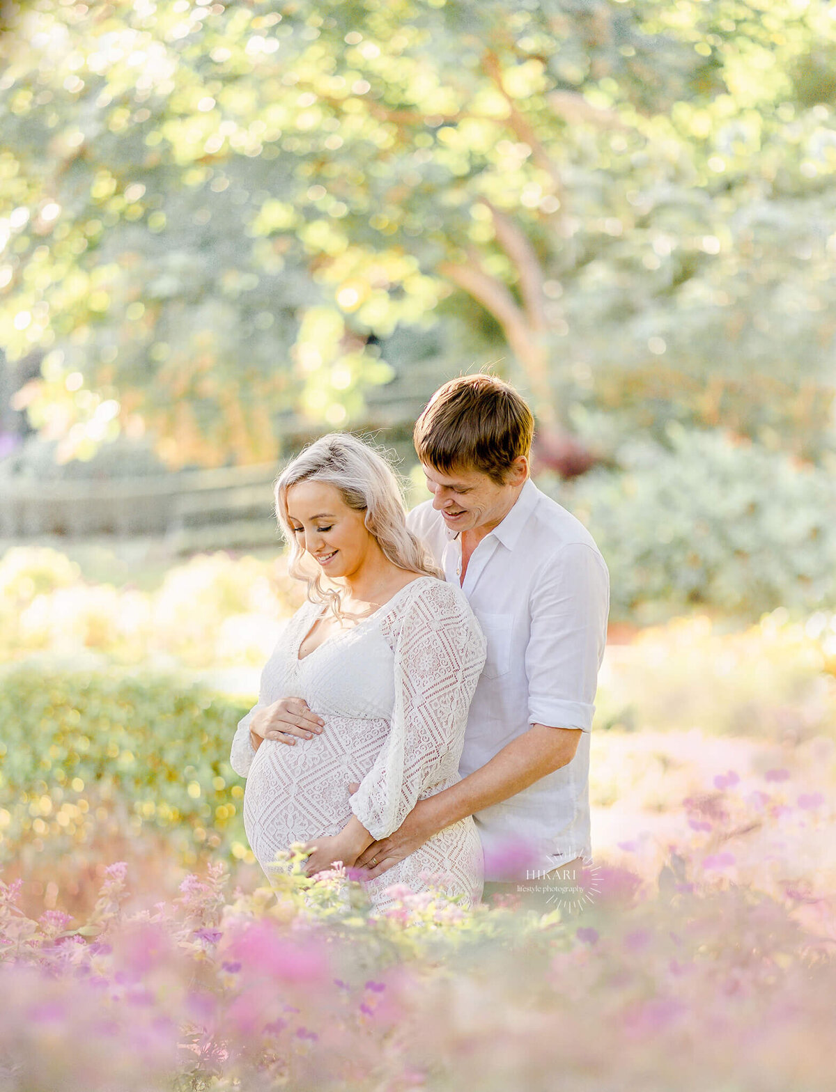 a candid shot of couple laughing during maternity photo session in roma street parklands flowers in brisbane near gold coast