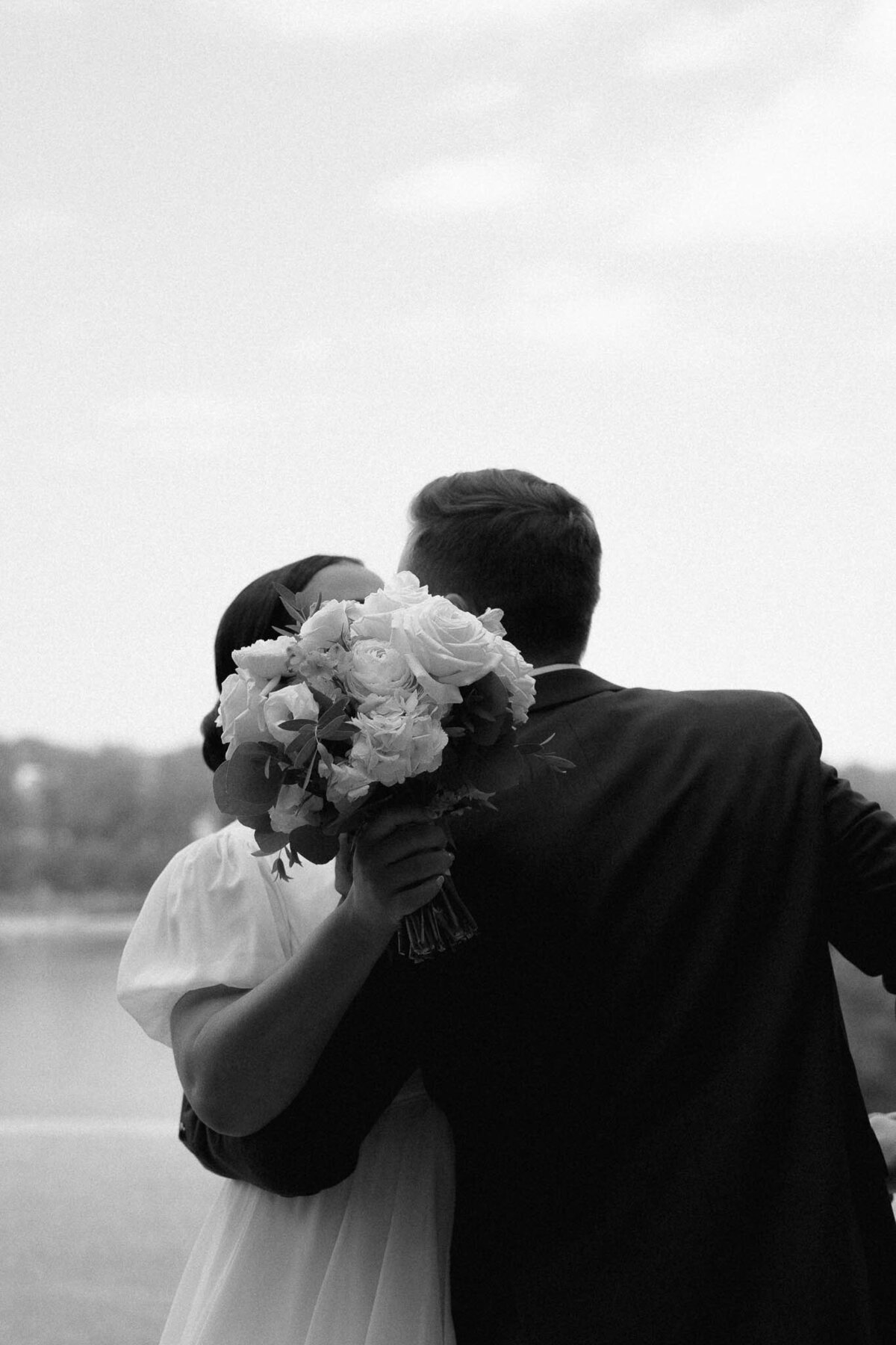 newlyweds kissing behind a bouquet of flowers
