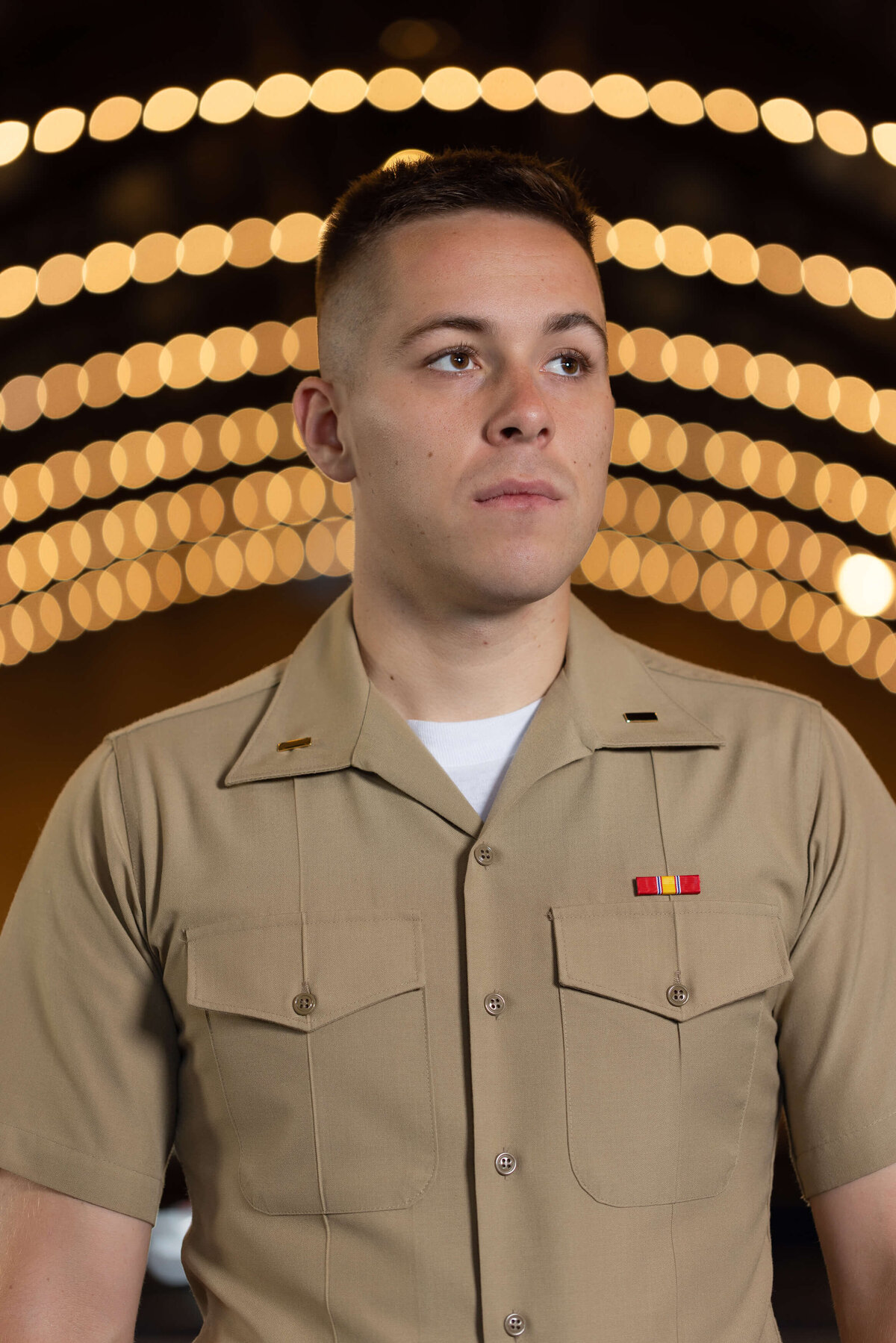 U.S. Marine Corps officer smiles with bokeh lights background.