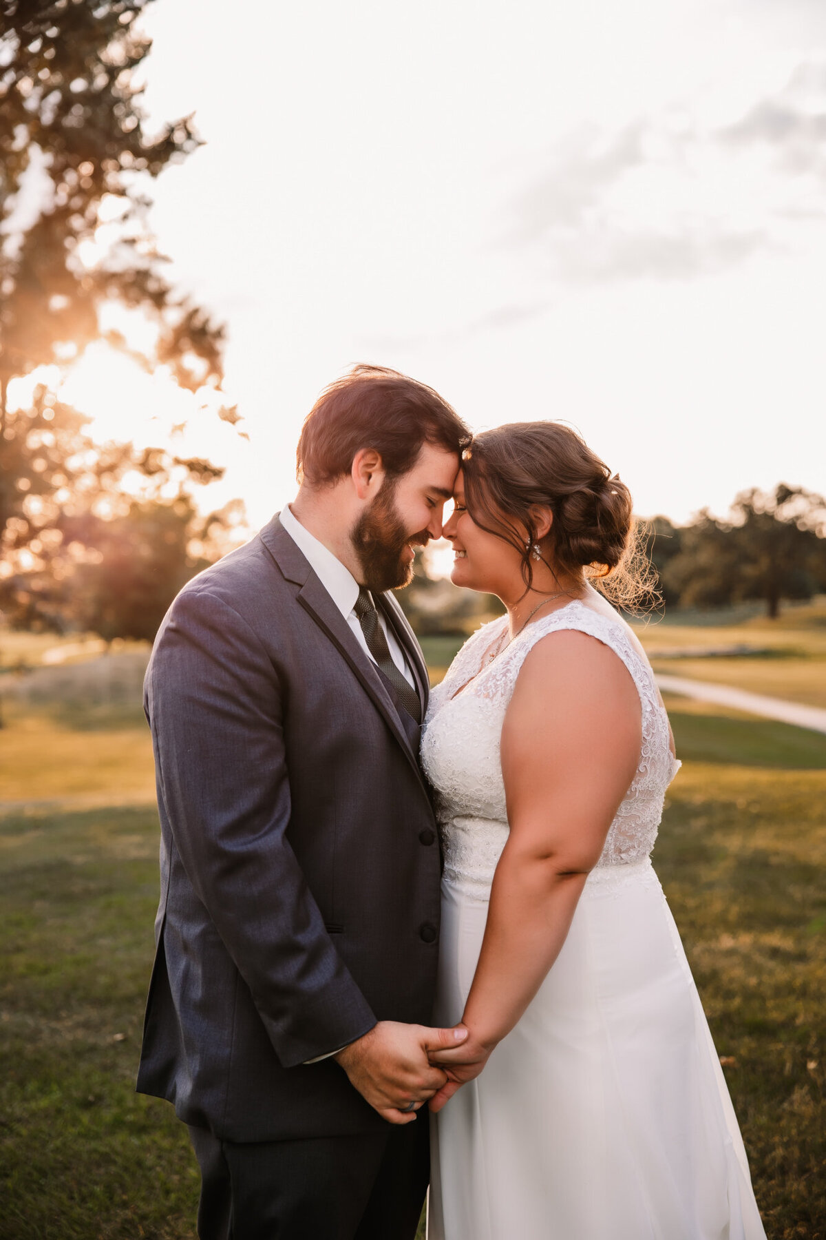 bride and groom hold hands forehead to forehead at sunset