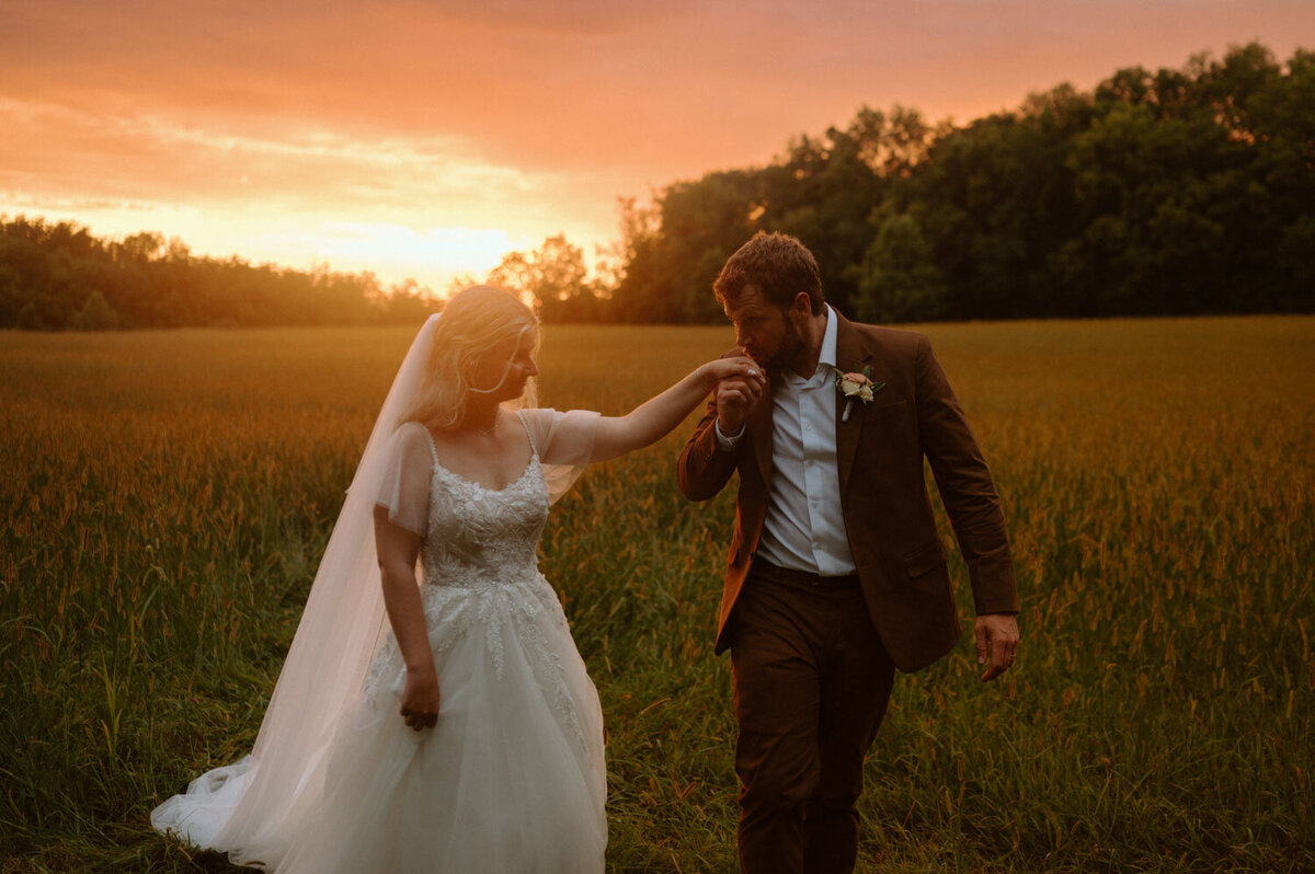 Bride and groom walking at sunset in a field