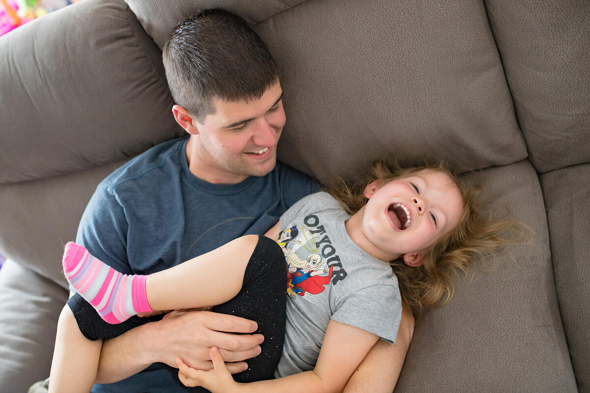 My husband tickling our daughter on the couch.