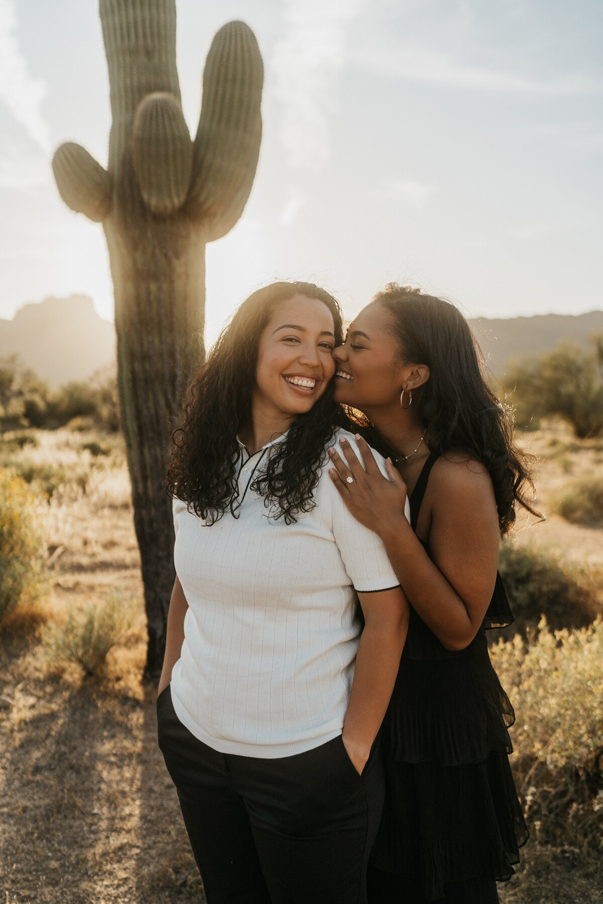A person standing behind their partner with their nose on their cheek 