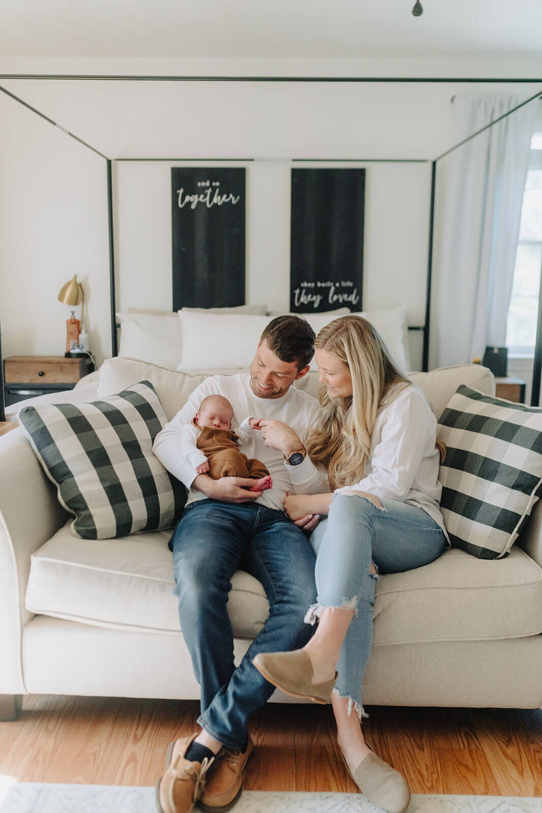 Couple sitting on sofa looking at newborn baby