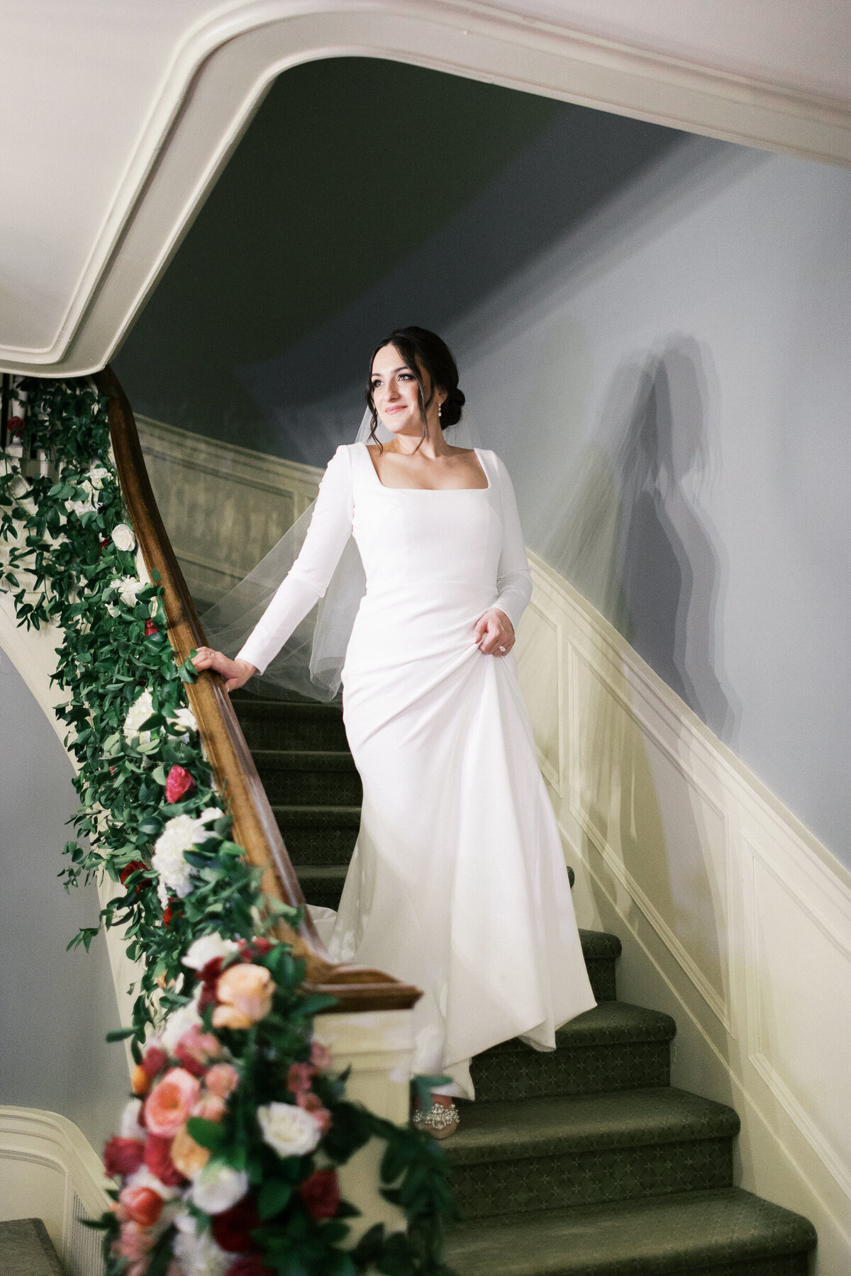 Bride in a white dress walking down the stairs with joy to see her man.