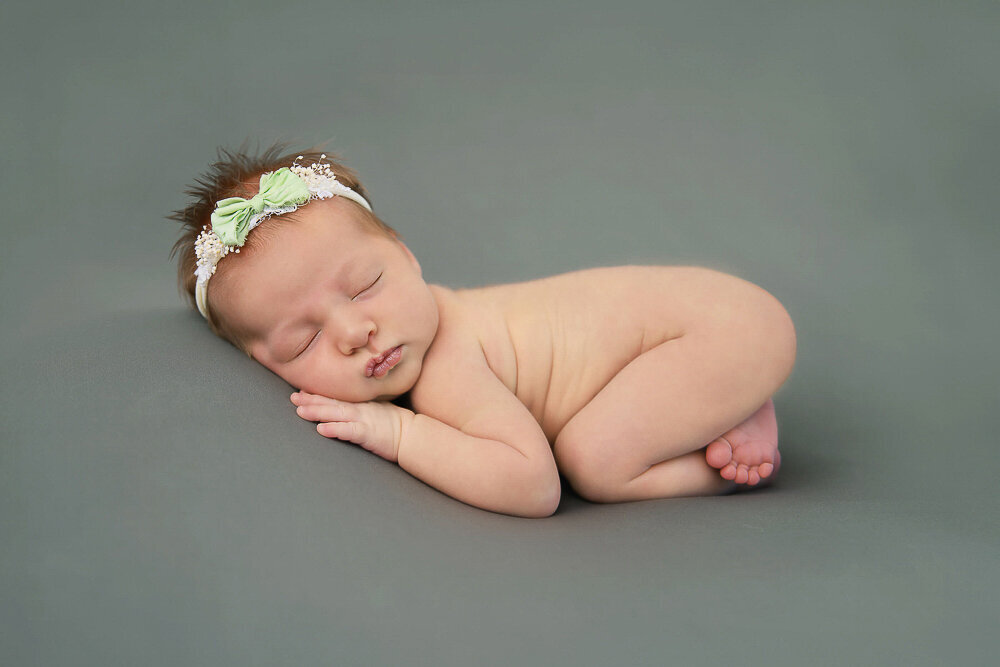newborn girl on a green background for her baby pictures.