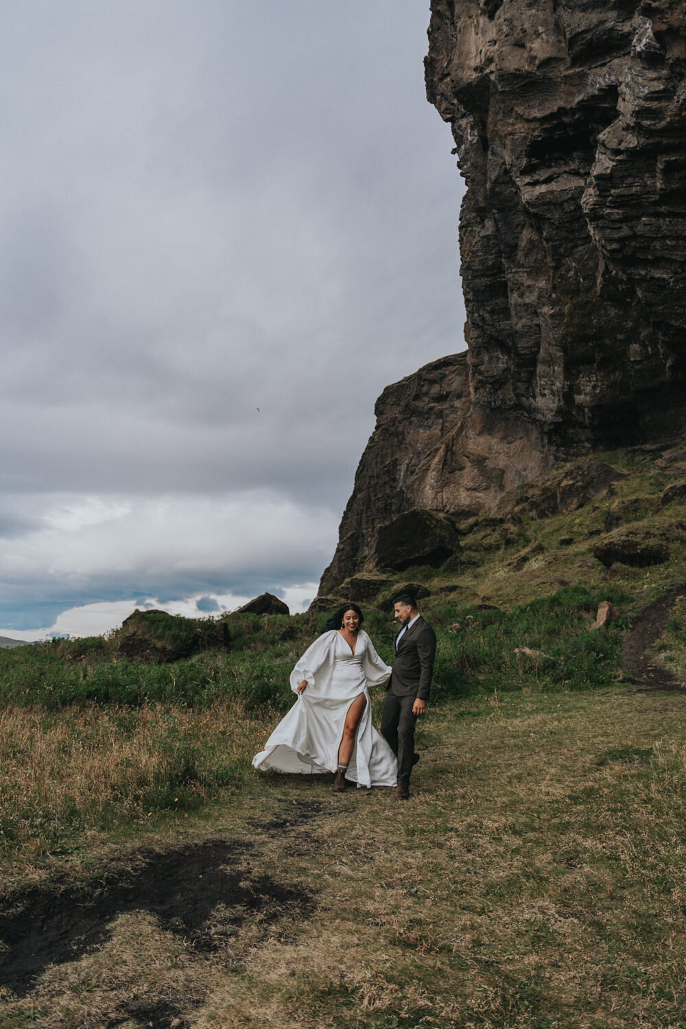 Husband and wife smile at each other while walking down an Iceland hill 