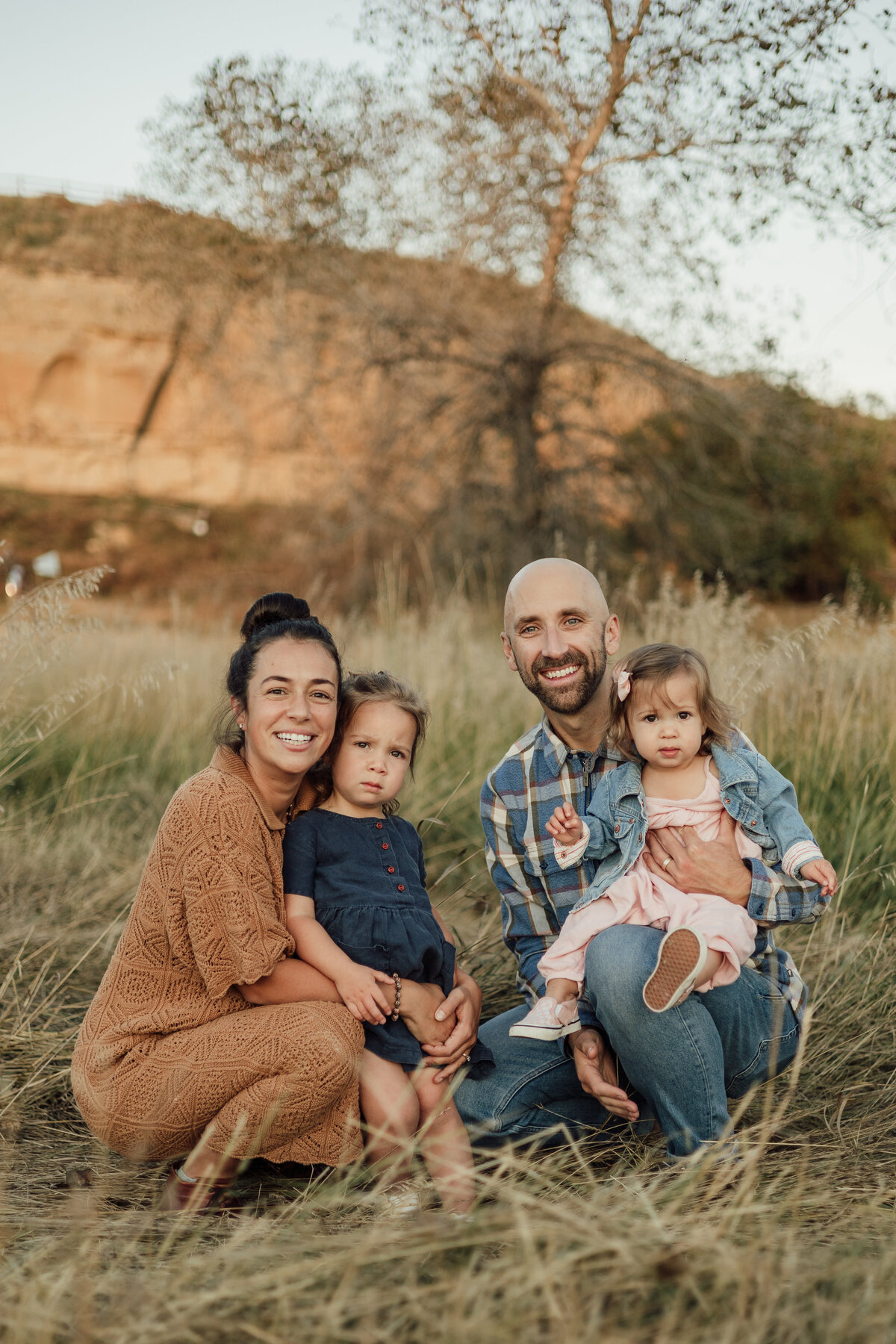 family of four smiling and looking at the camera during family session with alexis adkins photo in longmont colorado