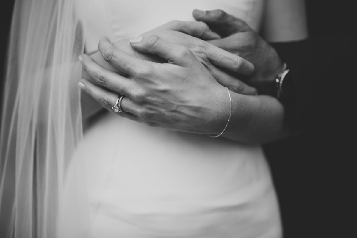 Close-up photograph of the bride and groom embracing of their hands