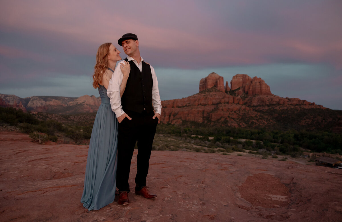 Couple standing against red rock backdrop during Sedona engagement session