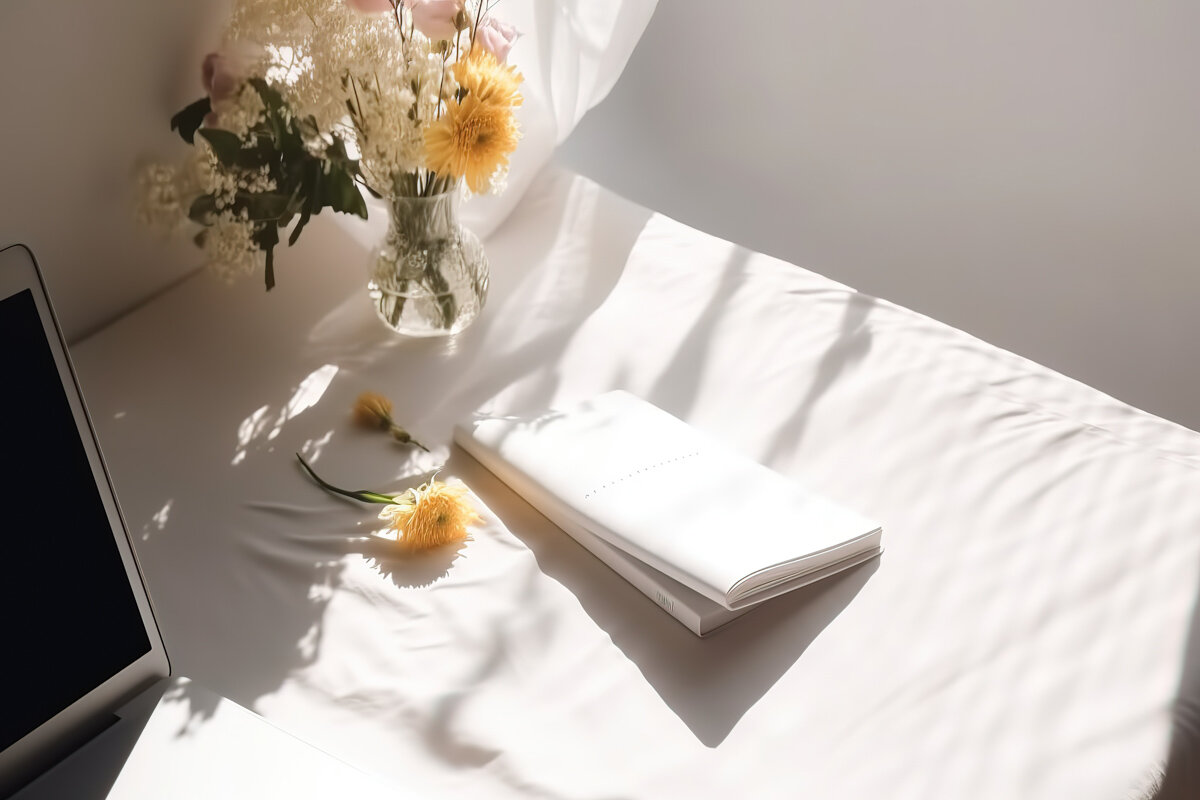 Laptop with bouquet of yellow flowers on a white desk