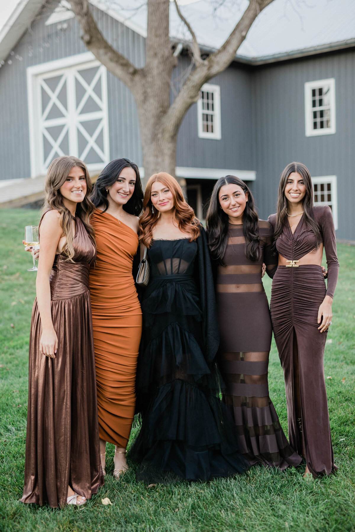 A group of five women stand on the lawn in front of a modern barn