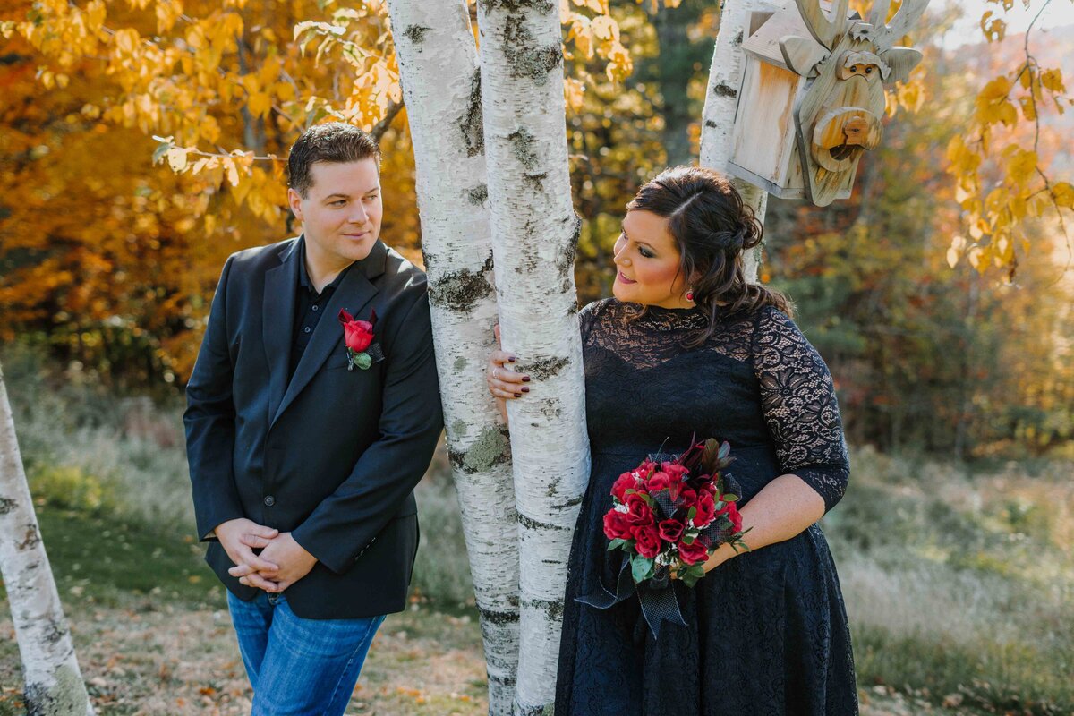 newly married couple dressed in all black next to a birch tree