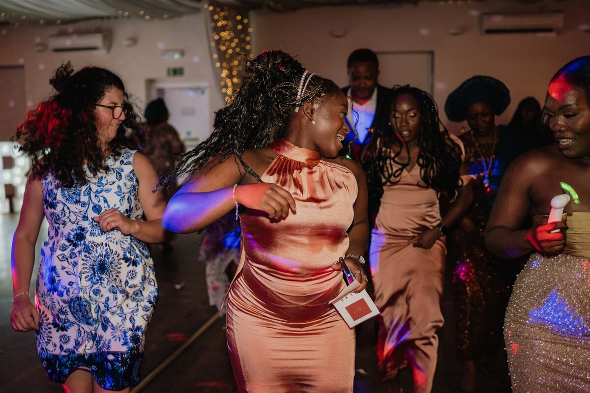 A large group of people dance together on a dance floor. They all face the same way and dance to a routine.