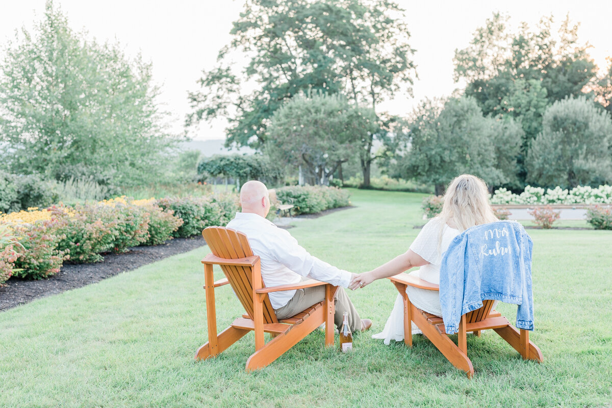 Couple in Adirondack chairs watching the sunset in Cazenovia, NY for their engagement photos