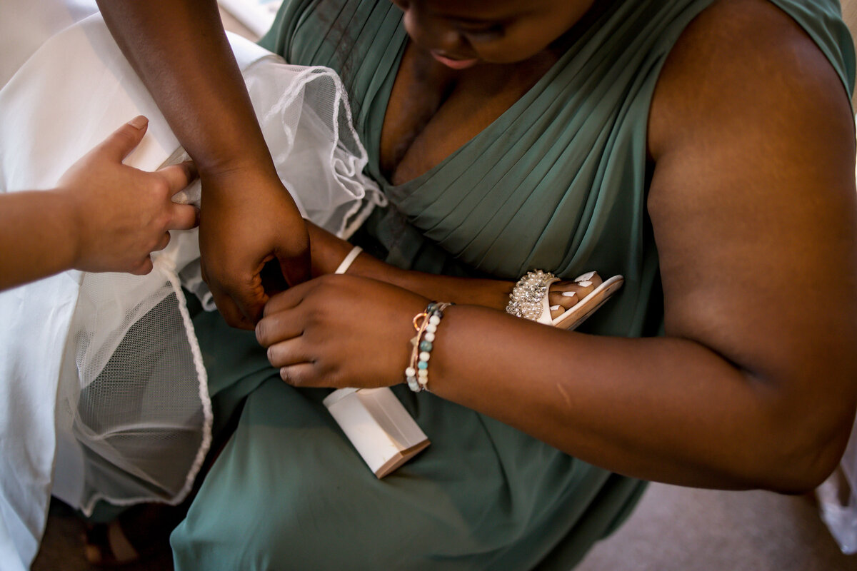 a bridesmaid helps the bride put her heels on
