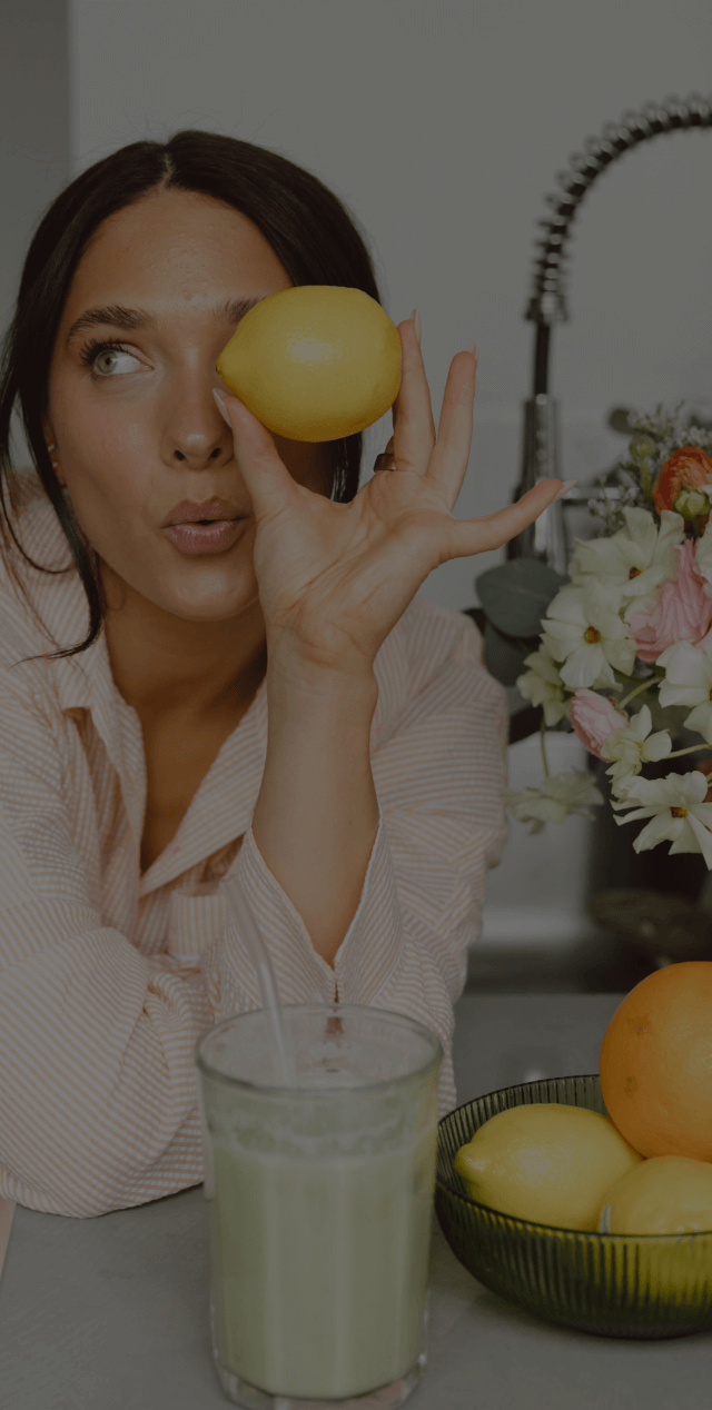 Picture of woman holding a lemon up to her eye, making a kissy face
