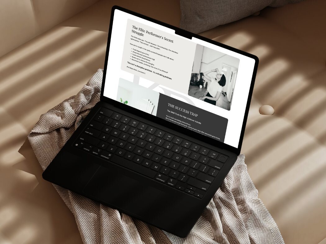 Black laptop on a soft beige cushion showing a coaching website with sections titled “The Elite Performer’s Secret Struggle” and “The Success Trap,” alongside a photo of a Kaya Ramjee