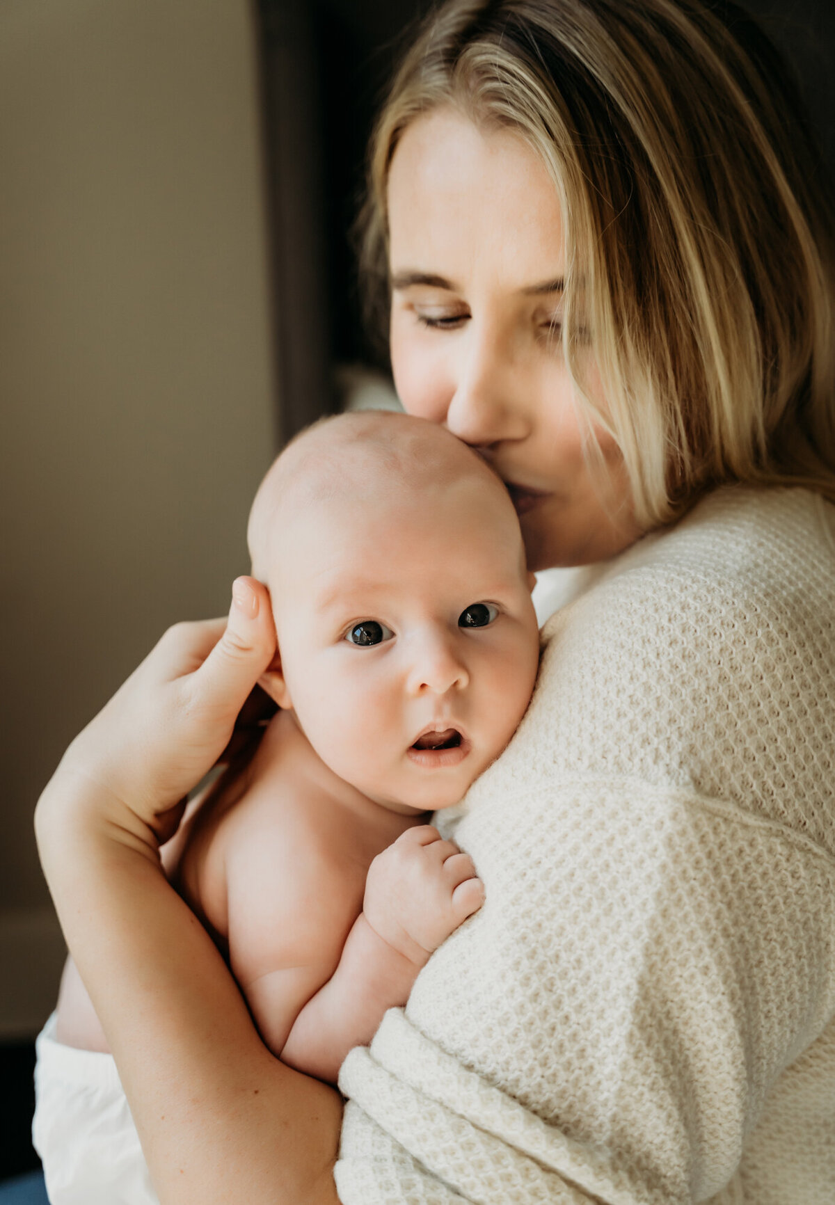 Newborn Photography, Mom holding baby girl as she gives her a kiss.