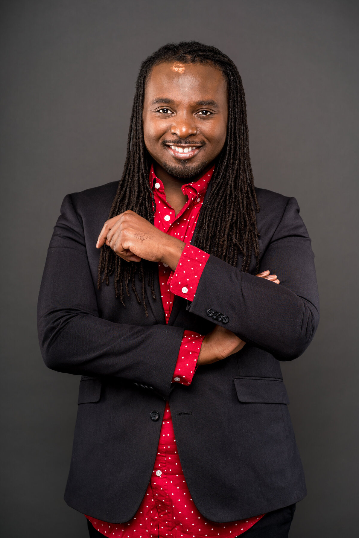 Black male with dreadlocks in blazer and red and white polka dot shirt
