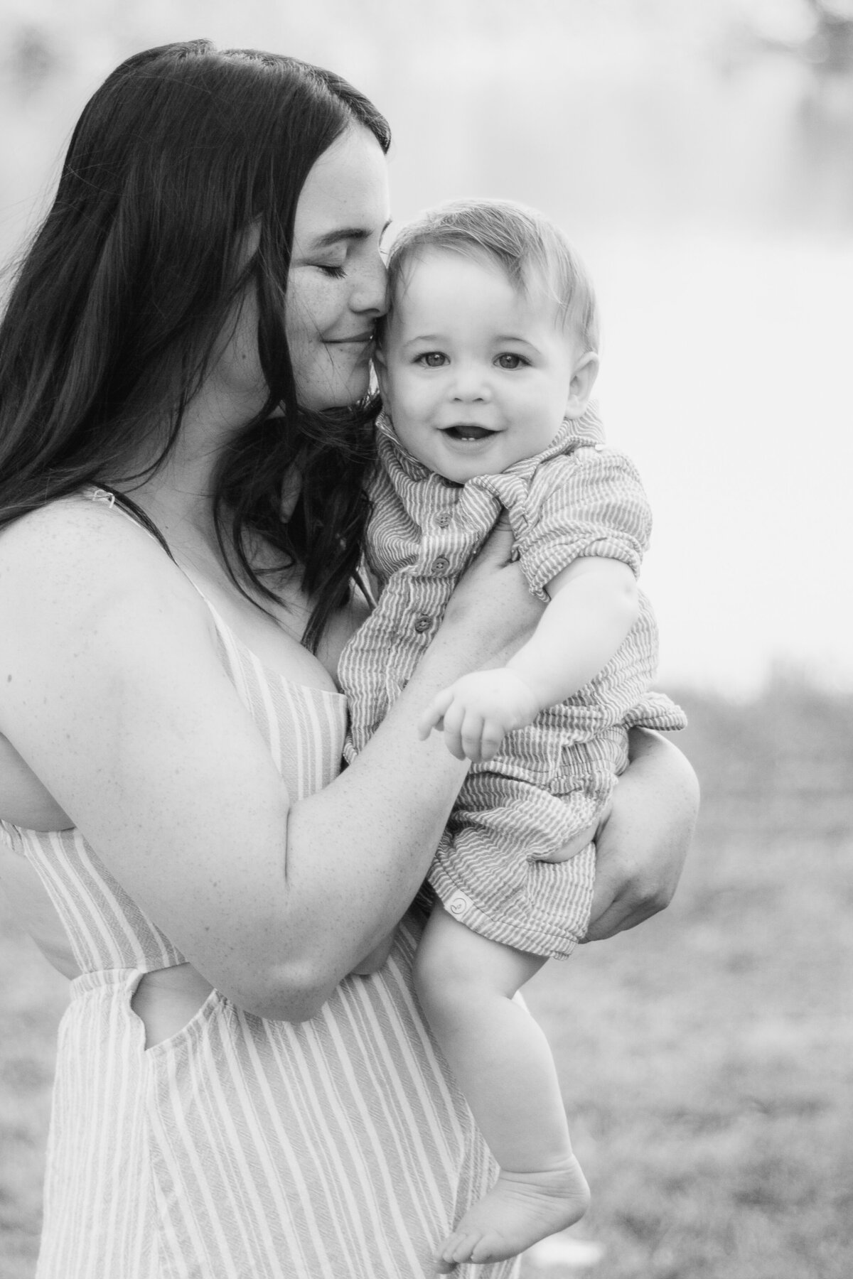 A heartwarming black and white image of a mother snuggling her laughing baby, capturing a tender and joyful moment.