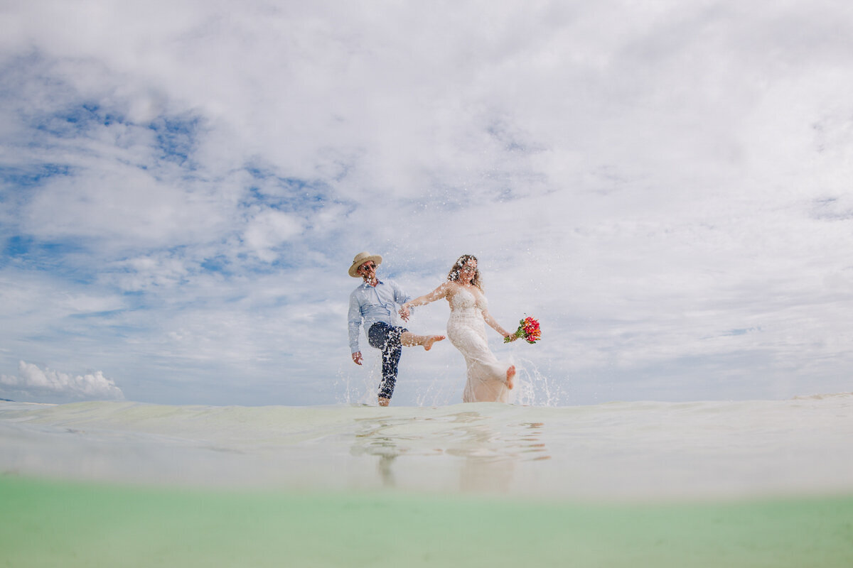 bride and groom splashing at the sandbar