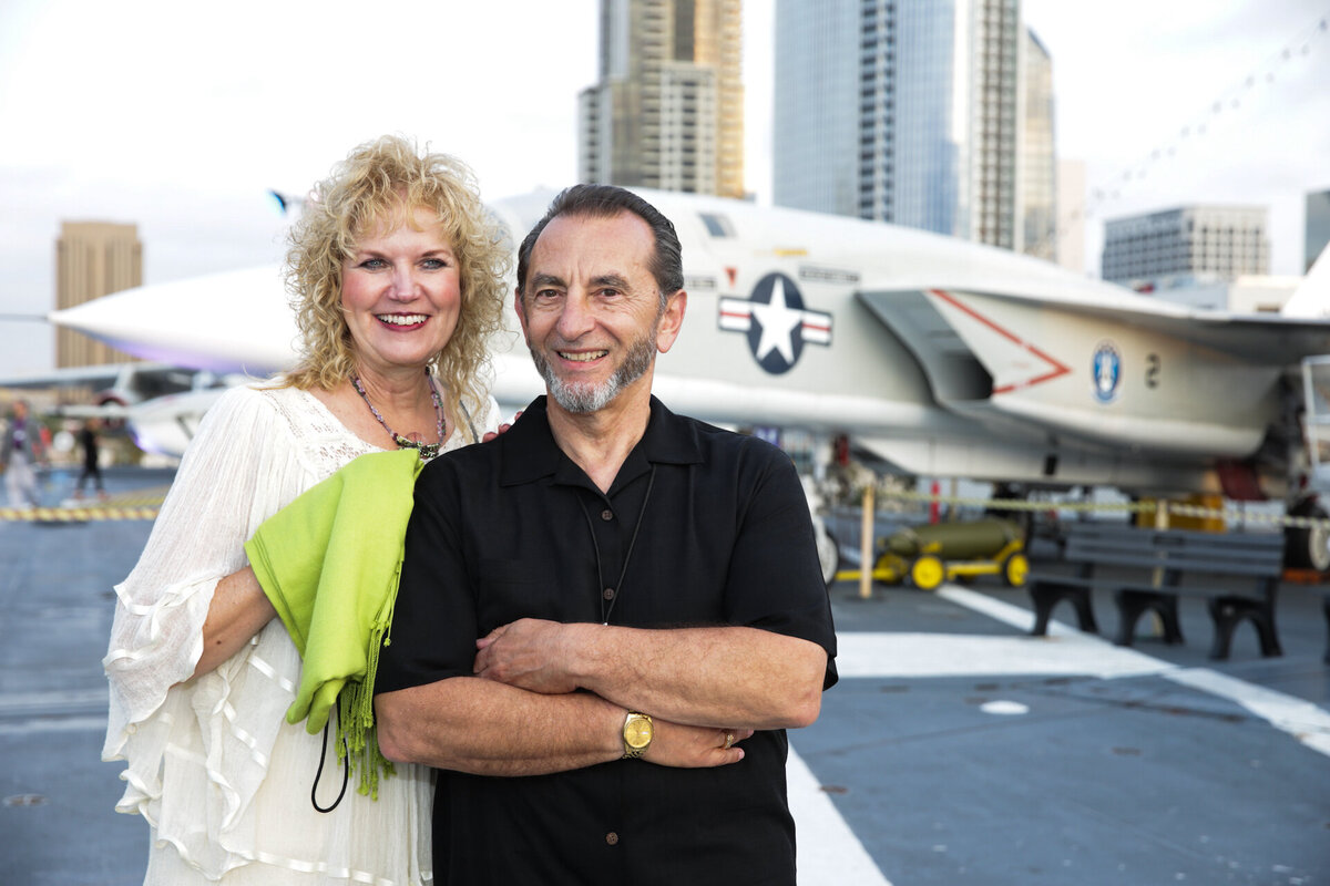 wealthy man and woman smiling standing in front of private jet