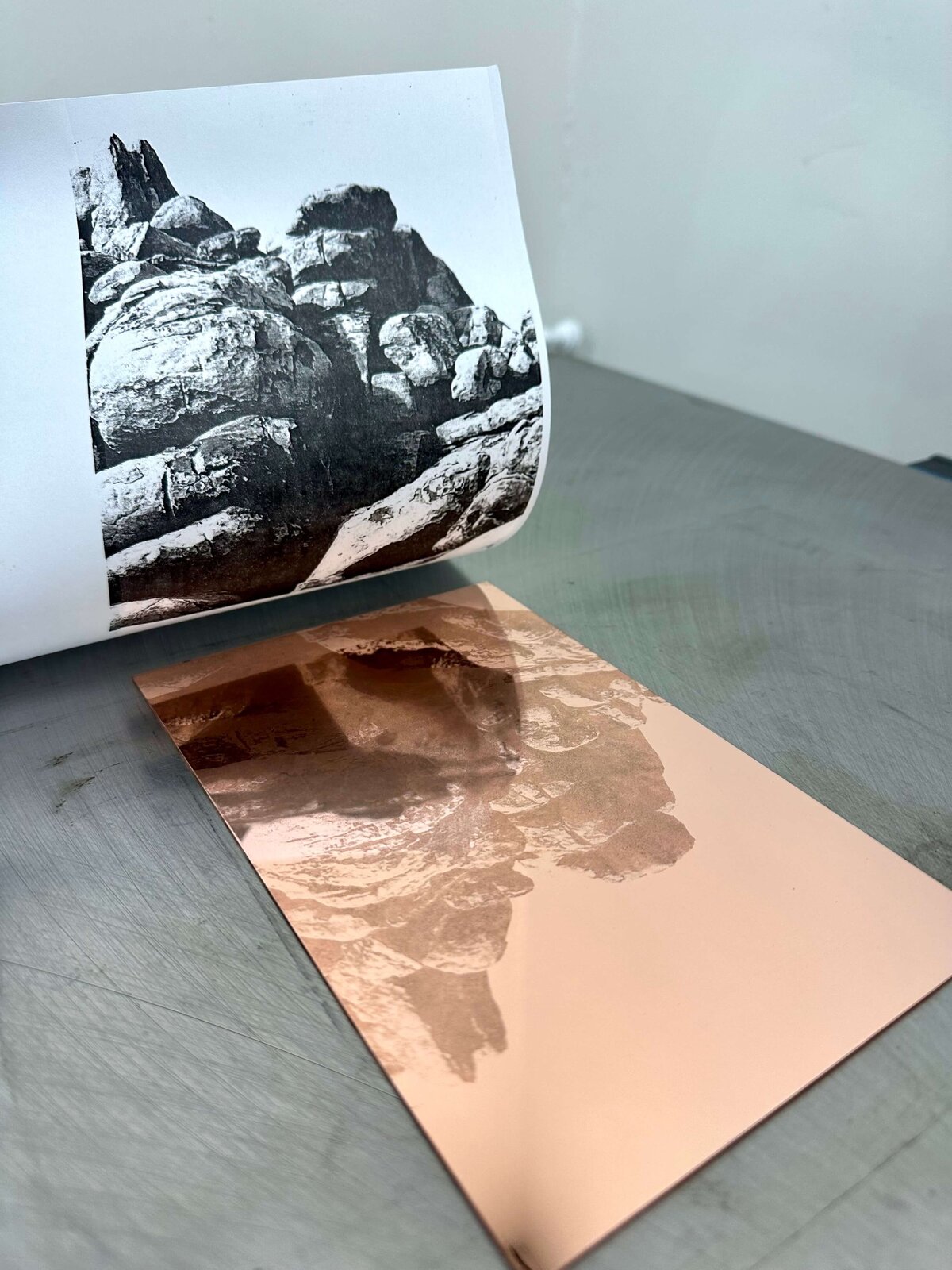 A printed rock photo laid over a copper plate showing a successful toner image transfer.