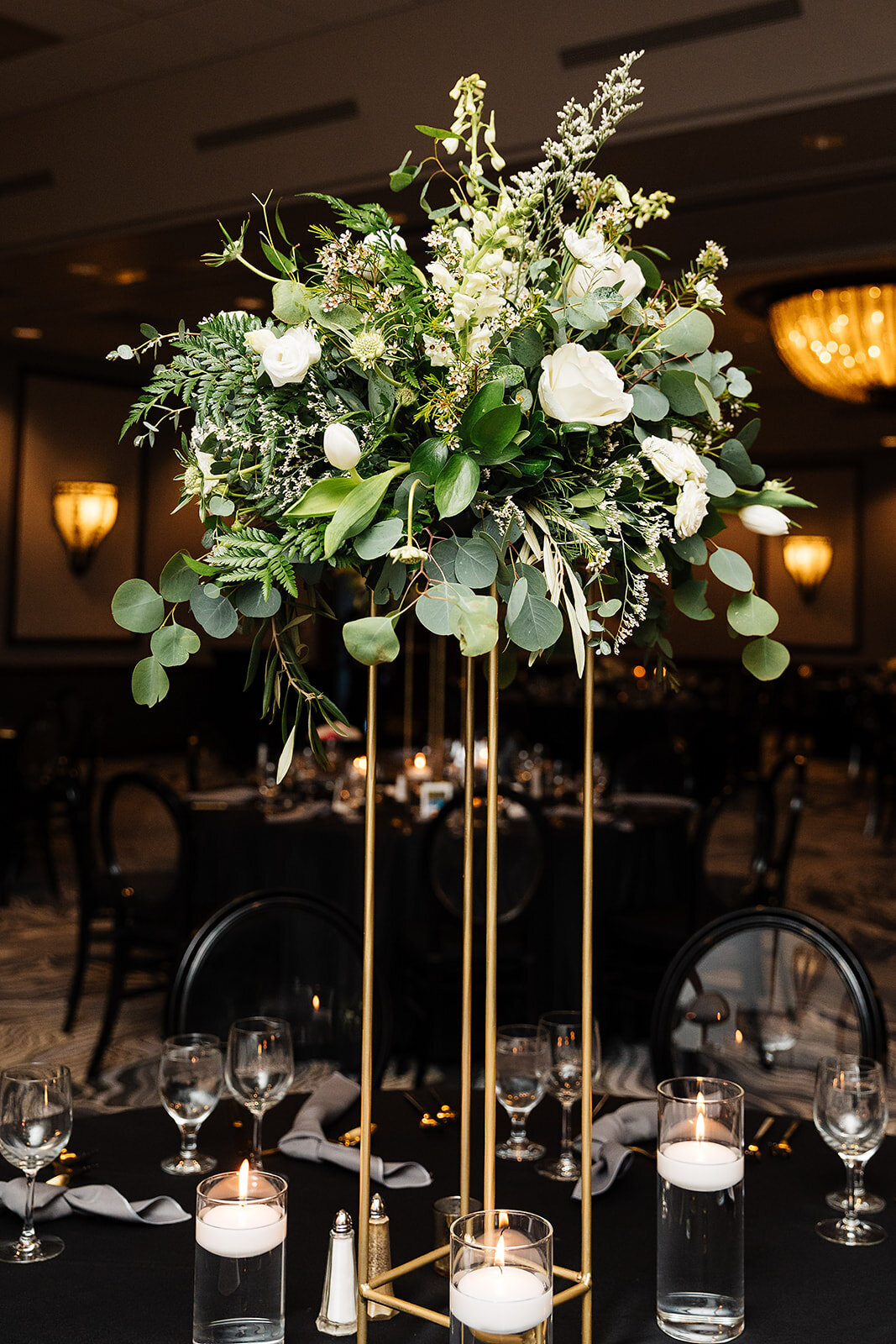 White and greenery lifted centerpiece on  a gold stand.