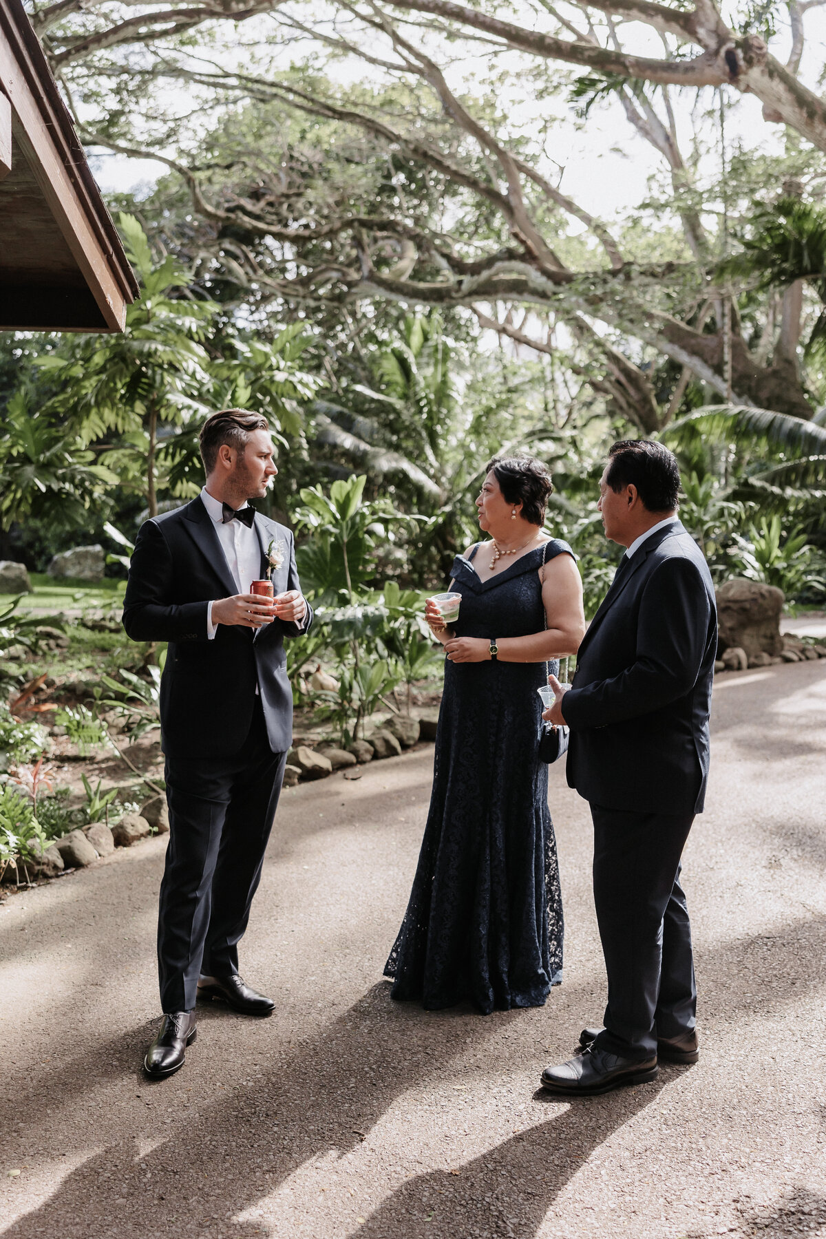 Groom standing with guests in front of a forrest at Kualoa Ranch